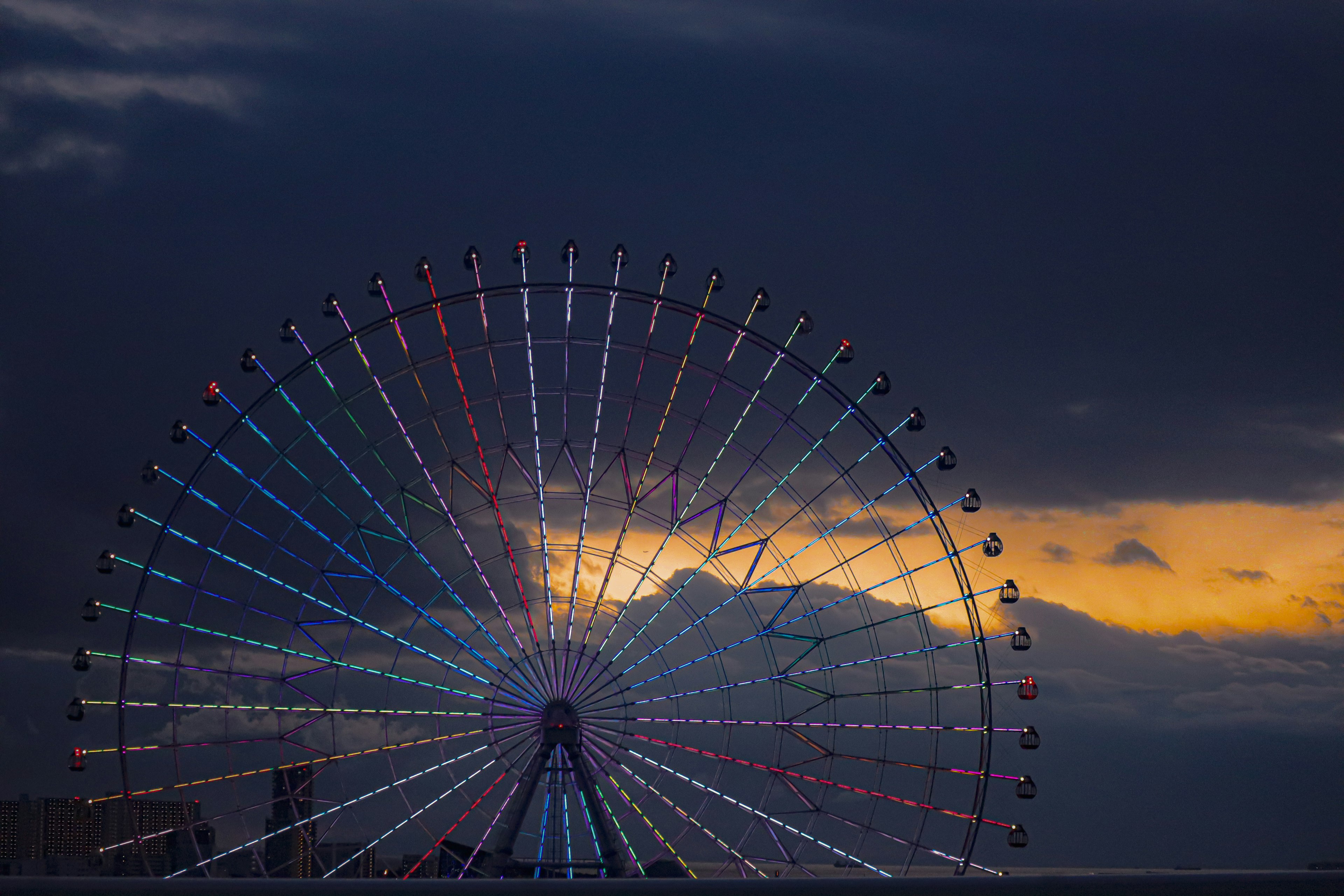 Colorful lights of a Ferris wheel against a sunset sky