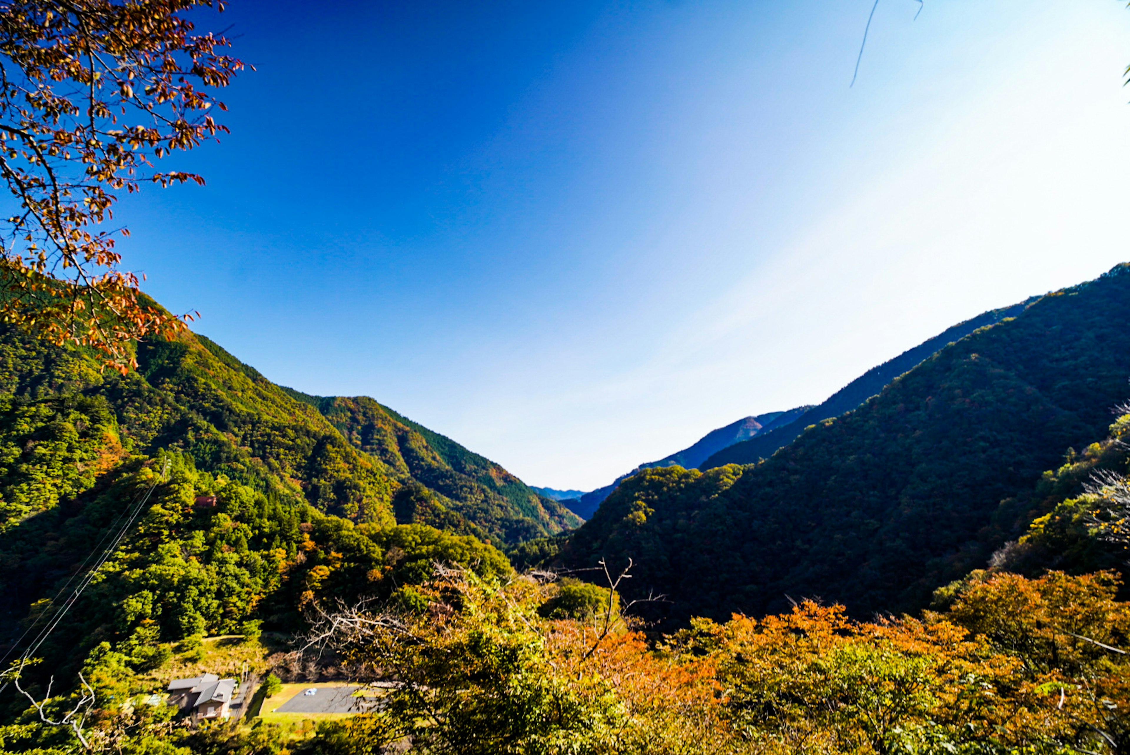 青空の下で緑に覆われた山々が広がる風景