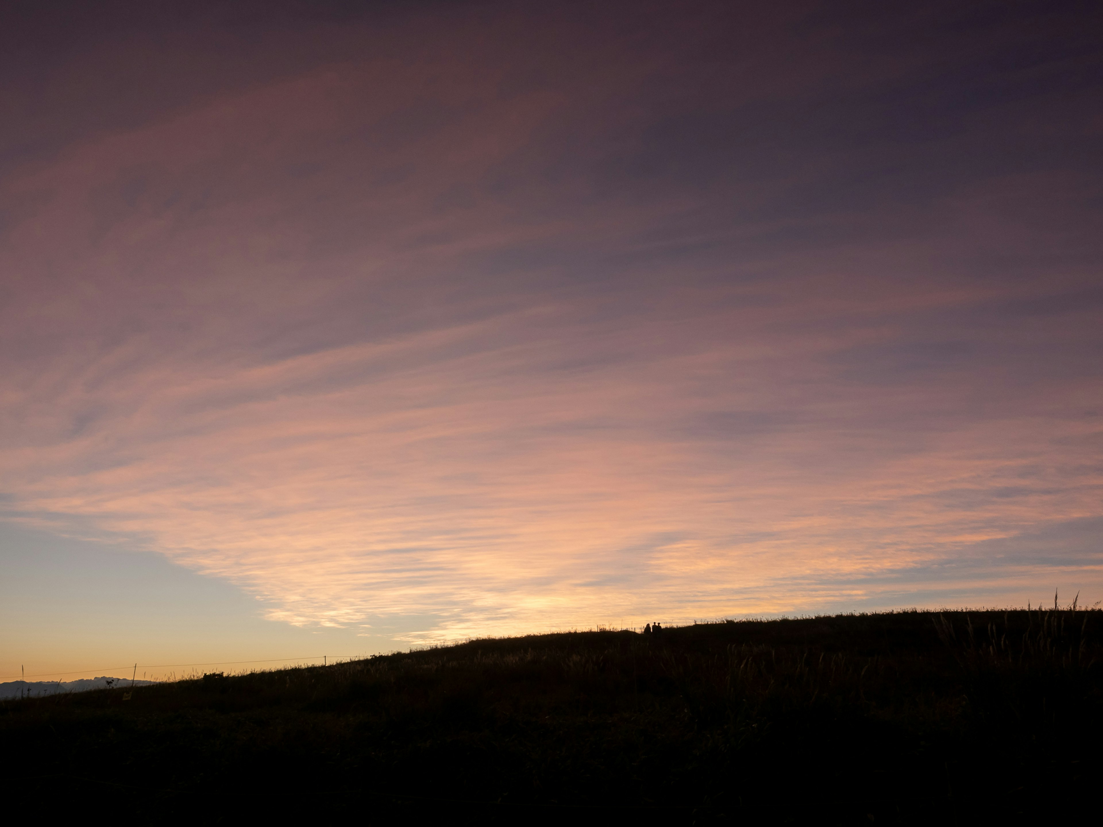 Cielo di tramonto pittoresco con tonalità morbide su una silhouette di colline