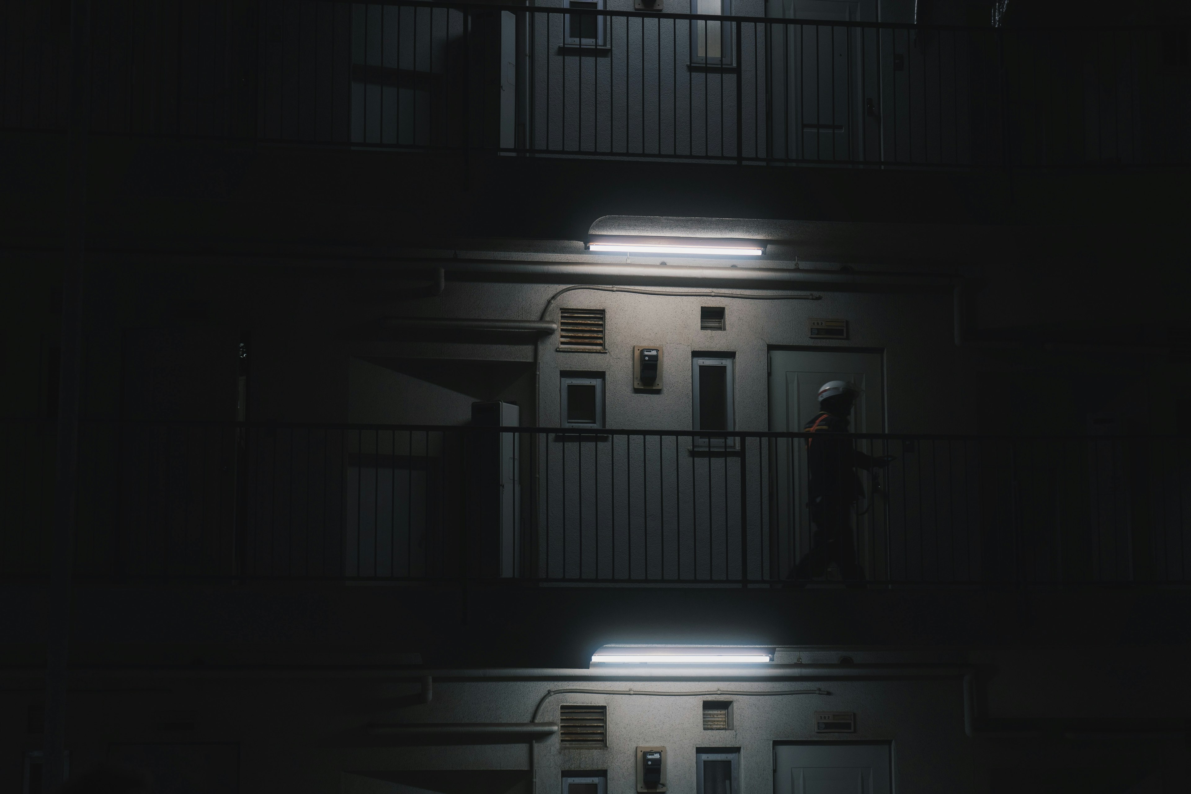 A person walking in a dark hallway with illuminated doors