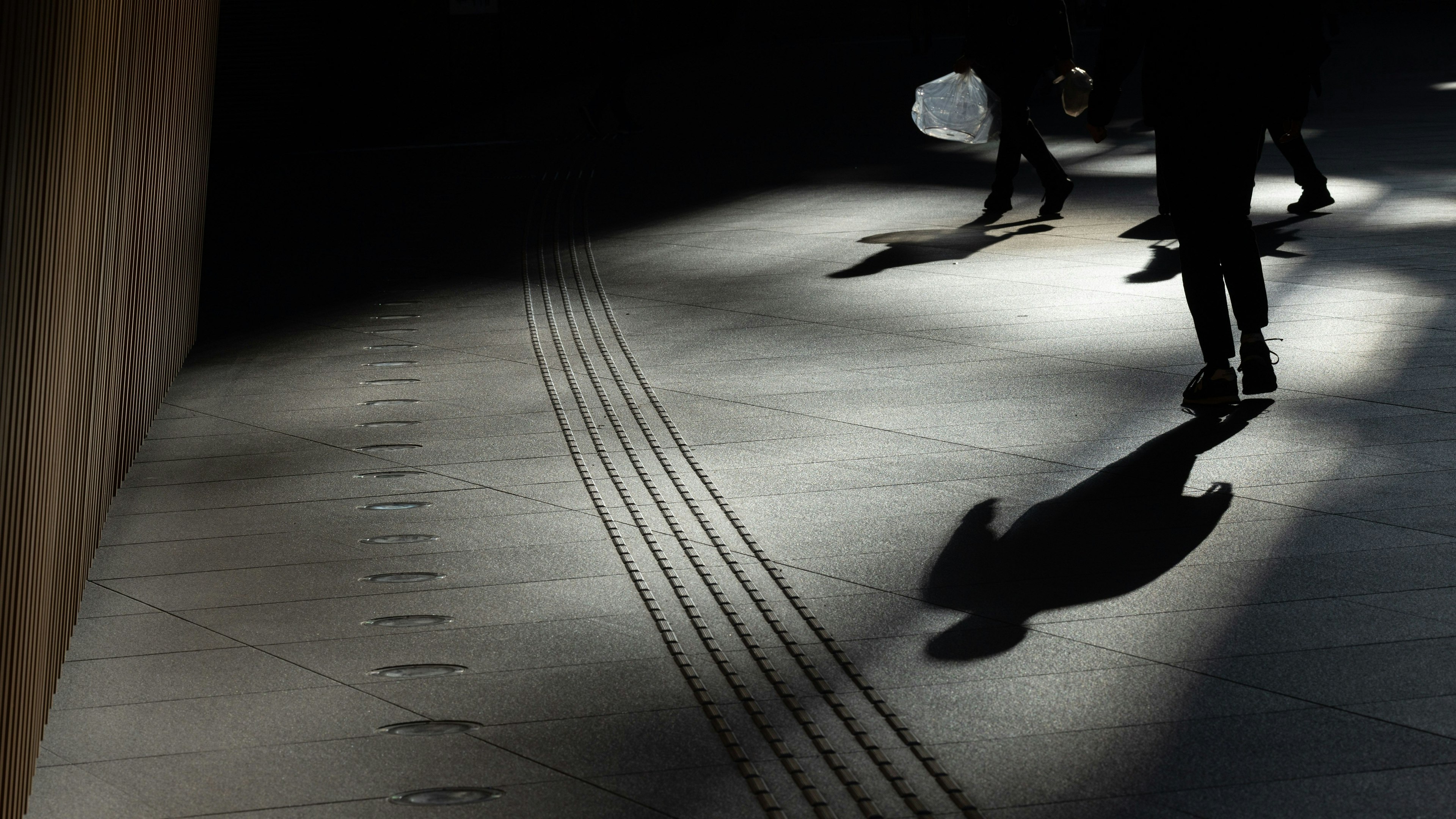 Silhouette di persone che camminano in un corridoio poco illuminato