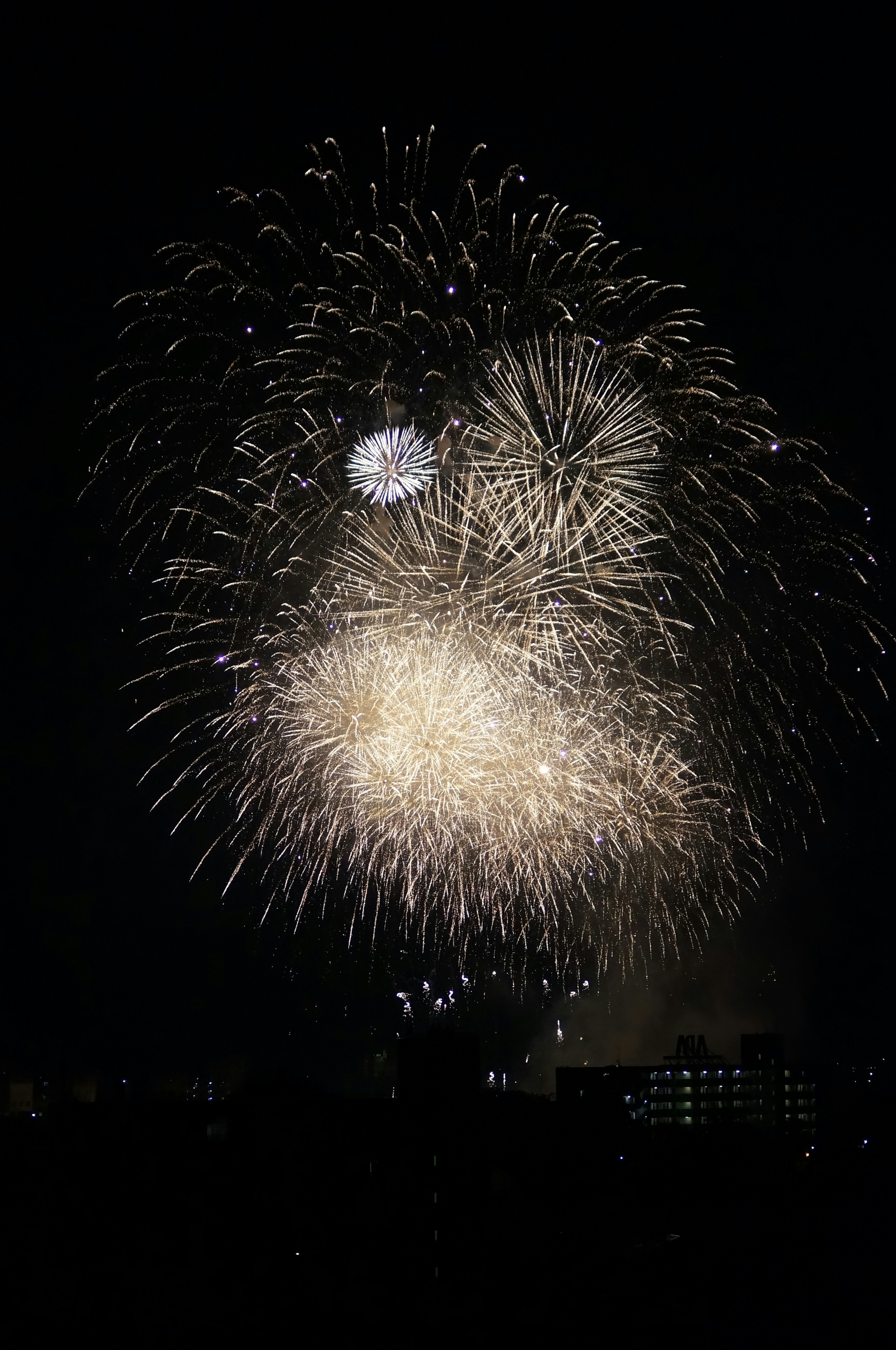 Helle weiße Feuerwerke, die am Nachthimmel mit kleineren Funken explodieren