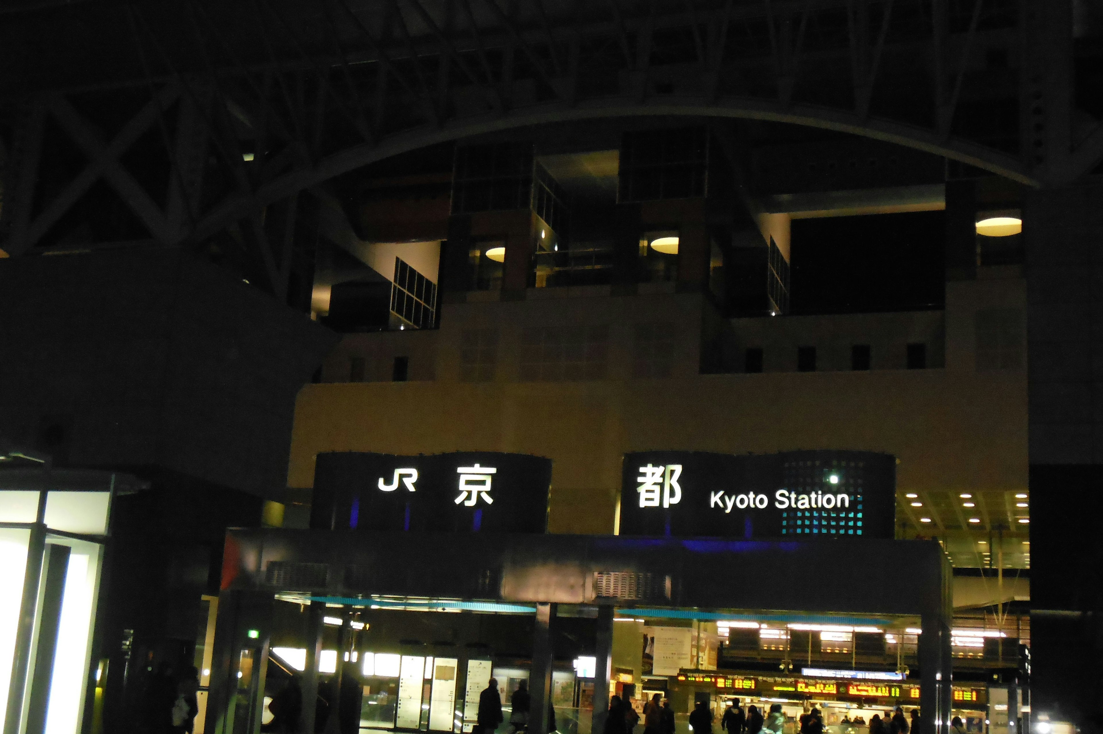 Vue nocturne de l'extérieur de la gare de Kyoto avec l'enseigne JR et l'affichage de la gare de Kyoto