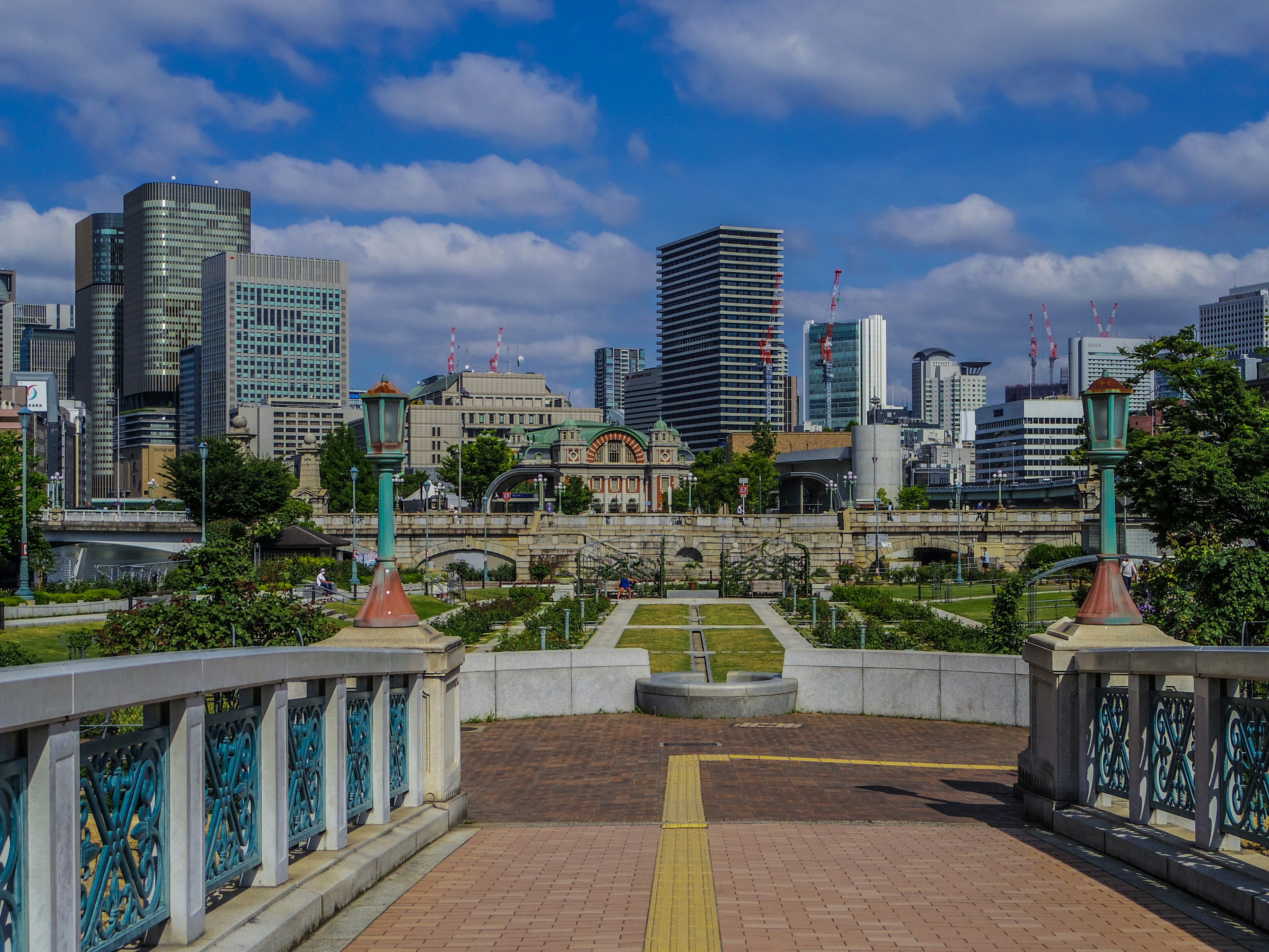 高層ビルが立ち並ぶ都市の風景に、緑豊かな公園と歴史的な建物が見える