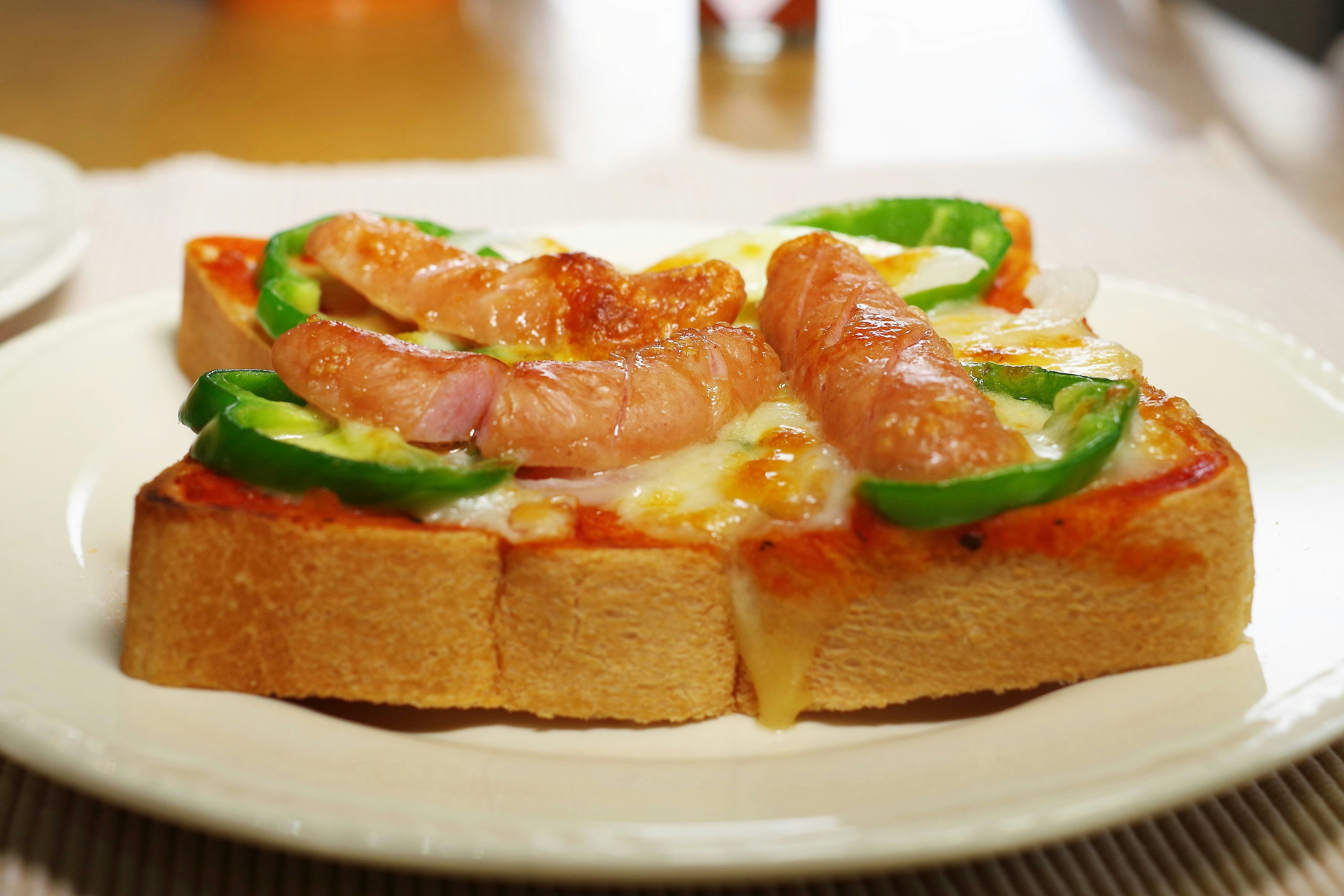 Tostada cubierta con salsa de pizza queso pimientos verdes y salchicha sabrosa