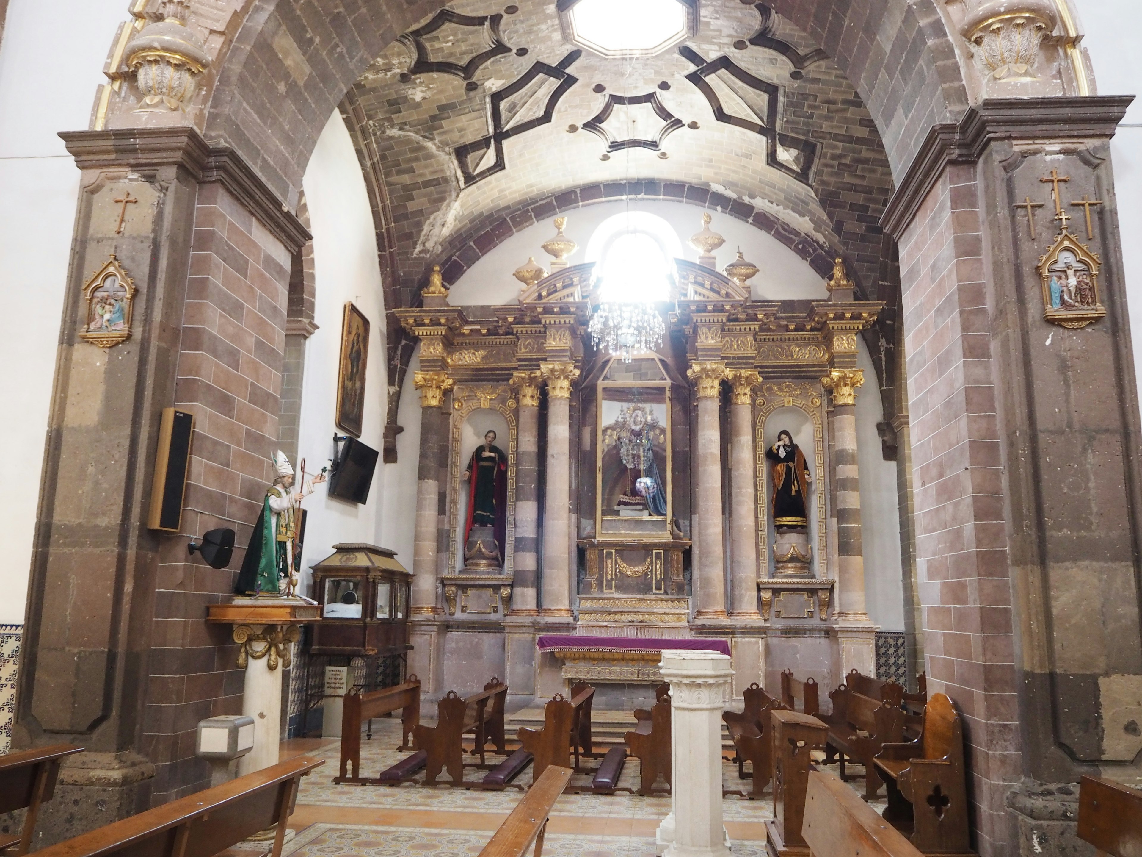 Interior de una hermosa iglesia con un techo decorativo y un altar dorado