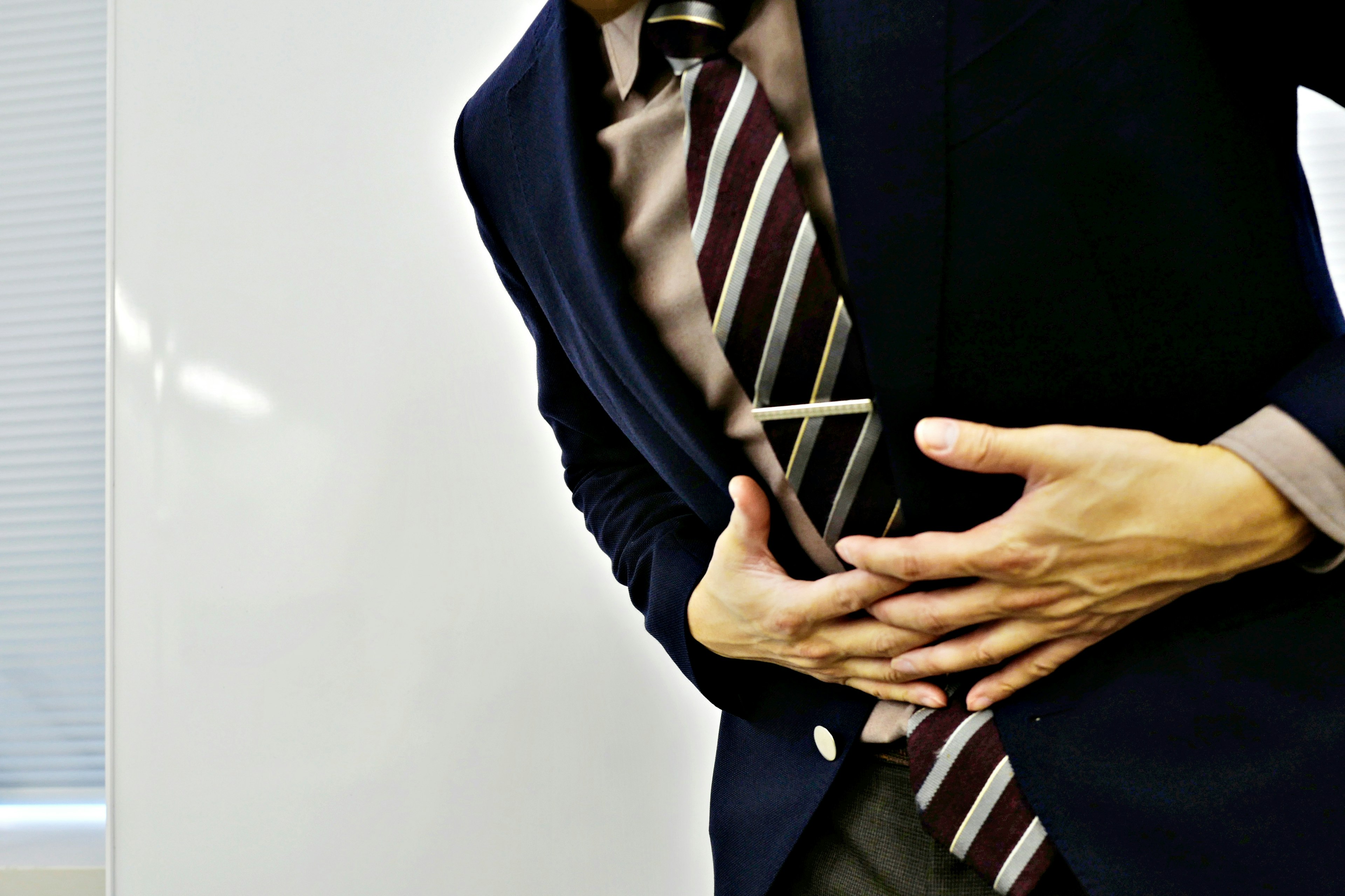 Hombre en traje sosteniendo su estómago