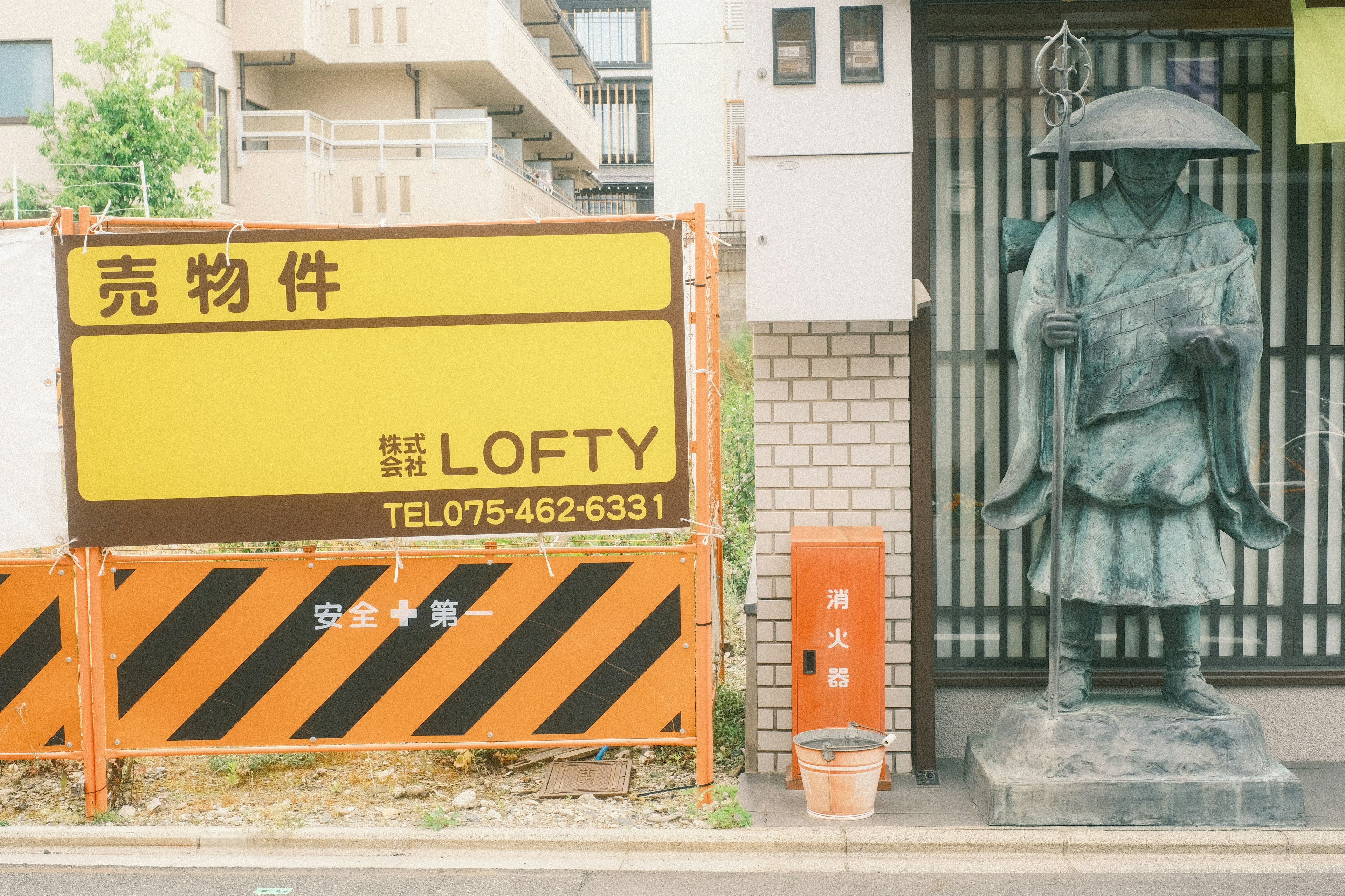 Scène de rue avec un panneau jaune et une statue en bronze à côté d'un feuillage vert