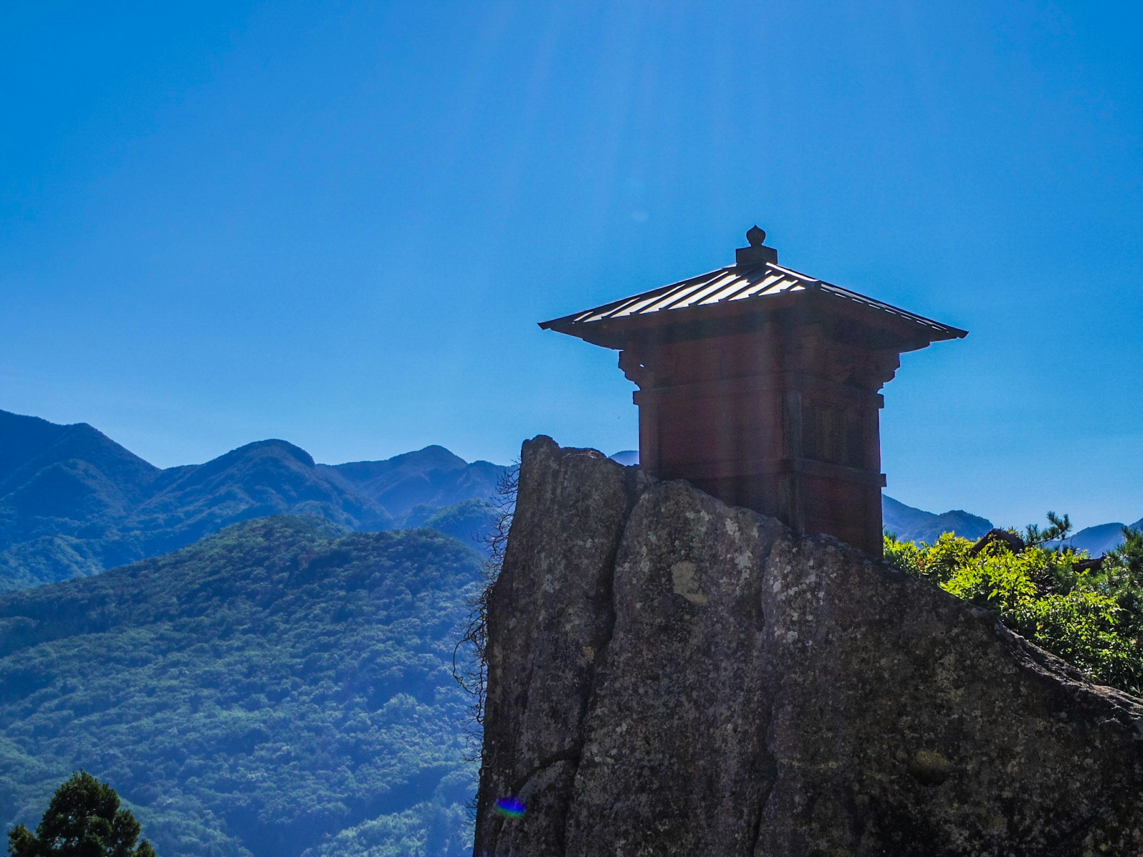 Una pequeña estructura similar a un templo situada en la cima de una roca bajo un cielo azul claro