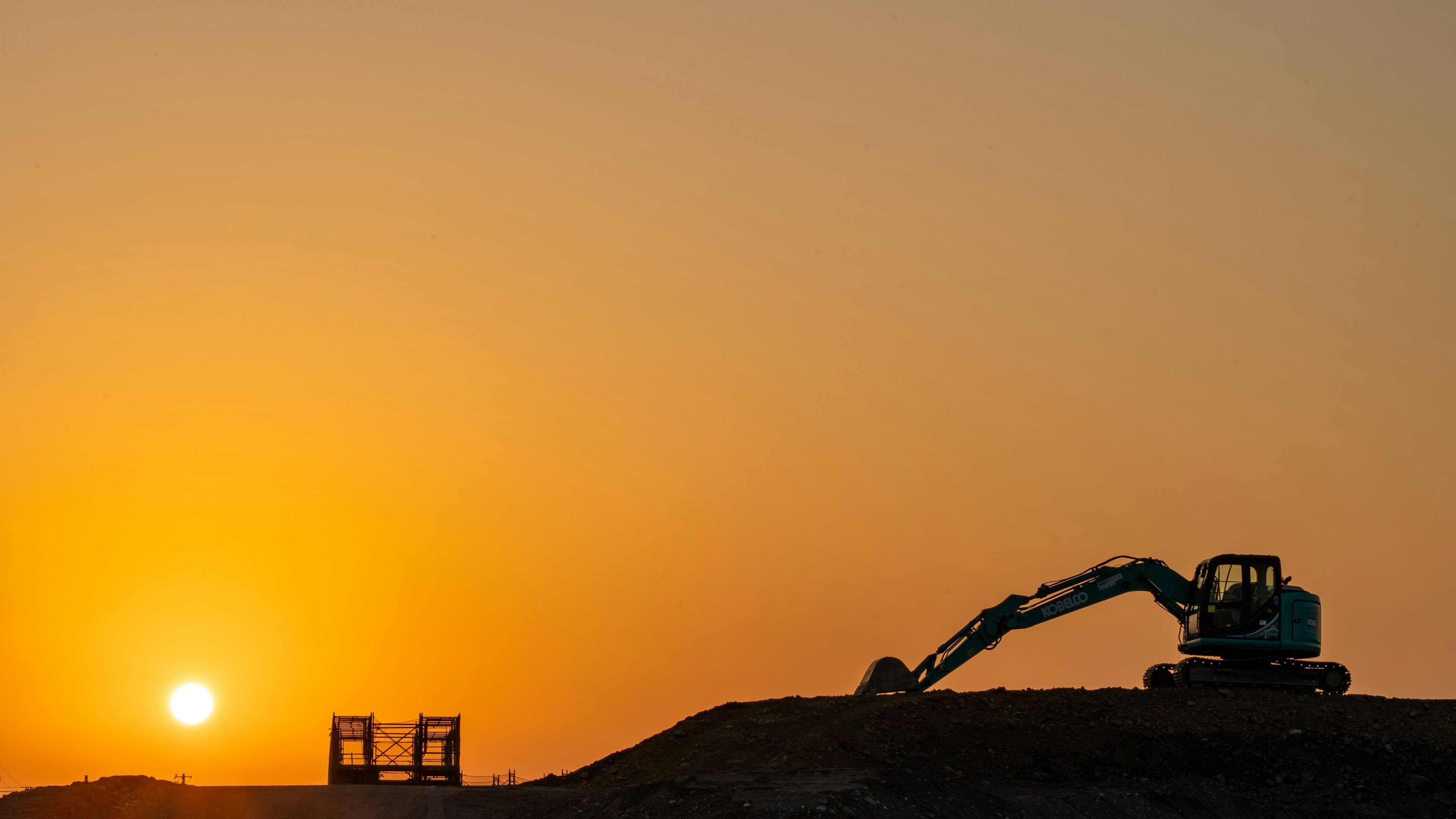 Silhouette of construction machinery against a sunset