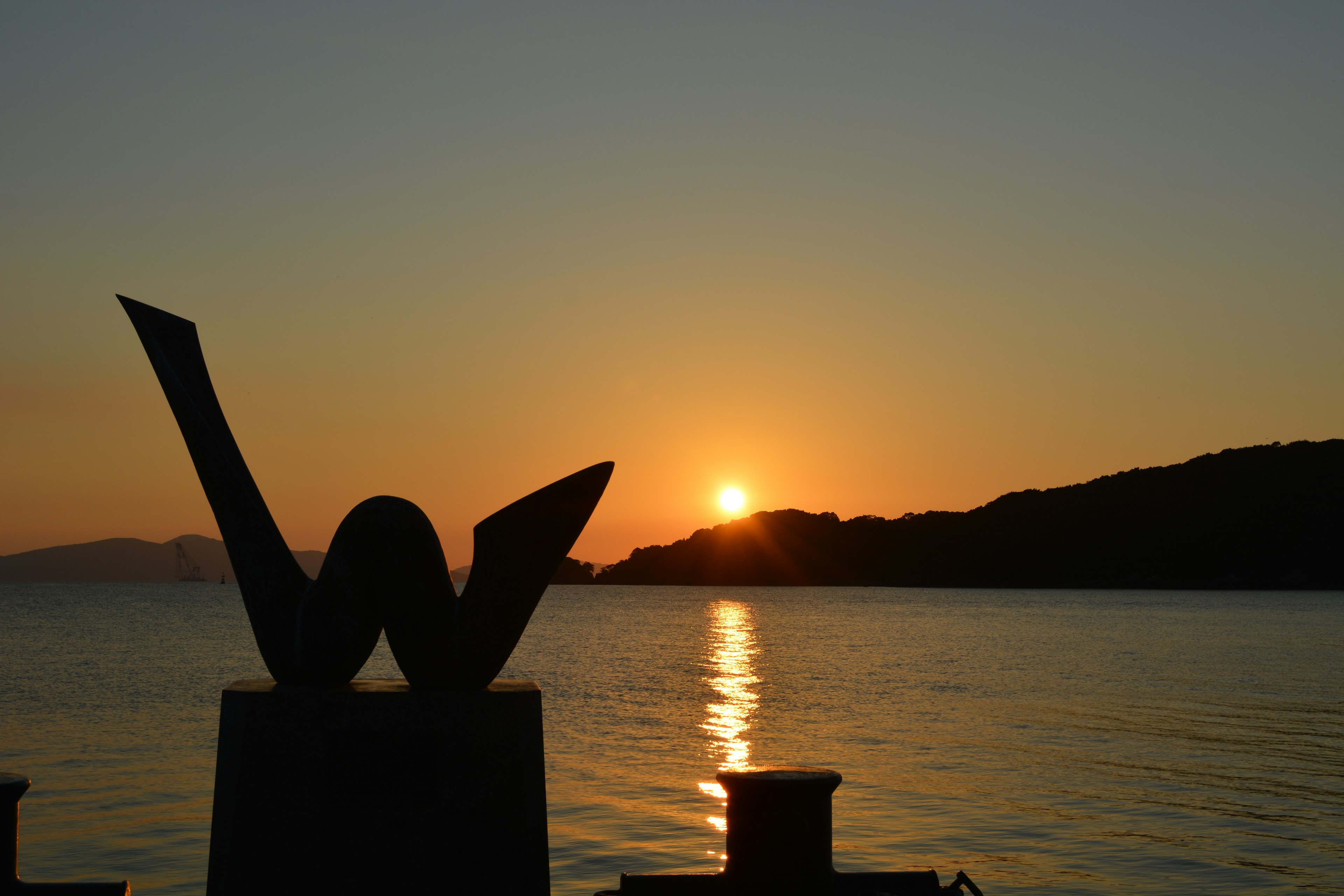 夕日が沈む海岸のシルエットと彫刻