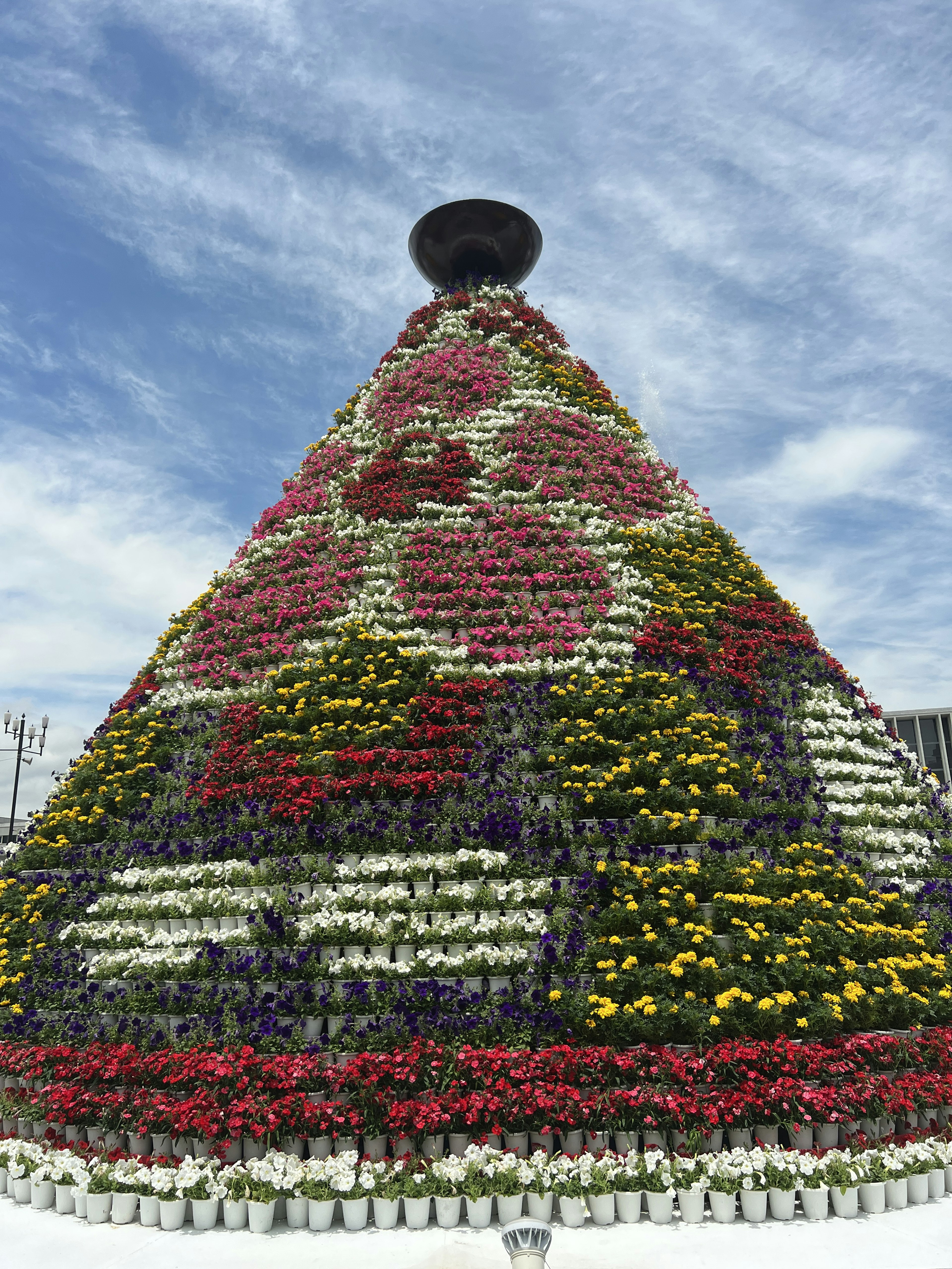 色とりどりの花で飾られたピラミッド型の構造物空に浮かぶ雲が背景