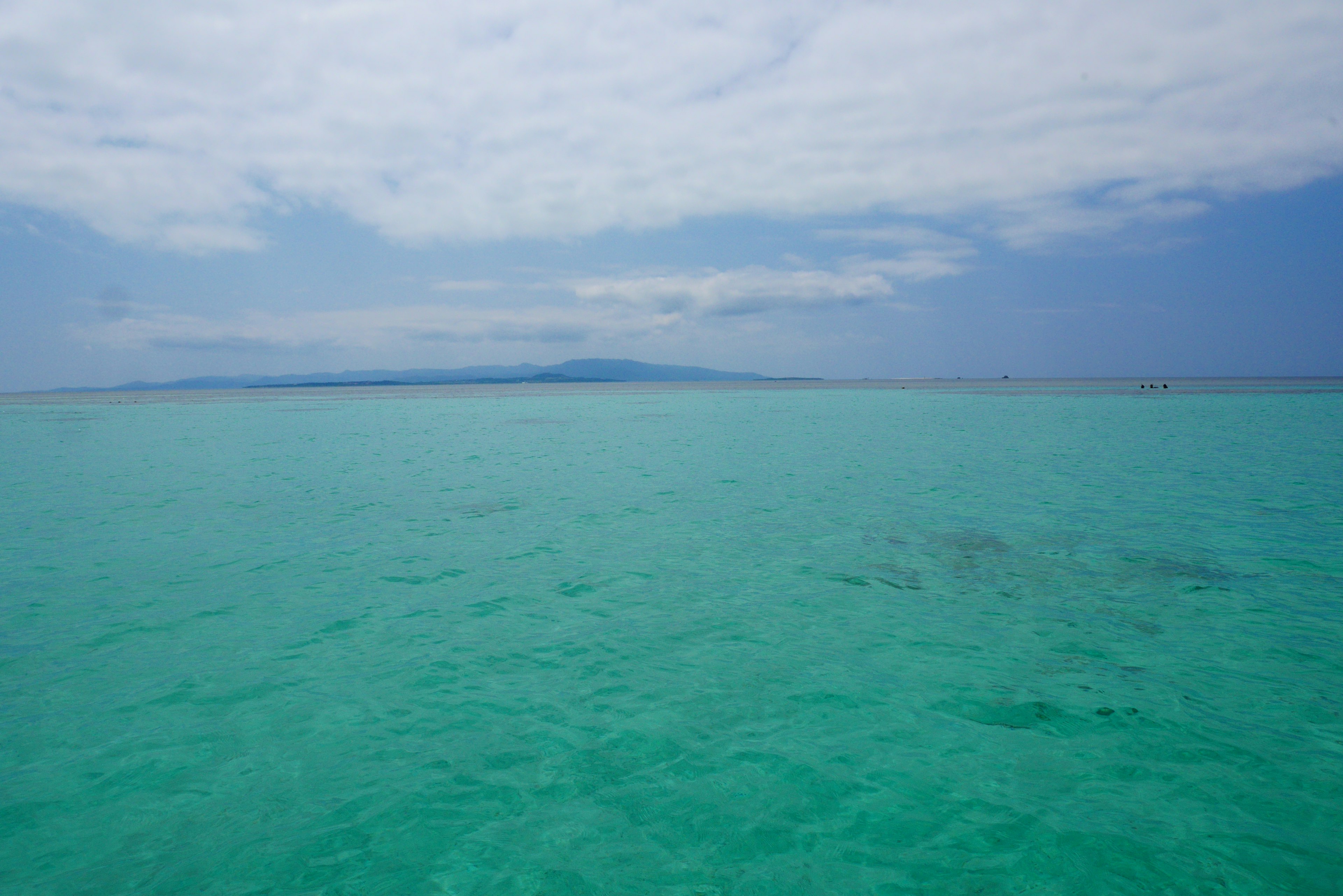 Lautan turquoise yang luas di bawah langit mendung