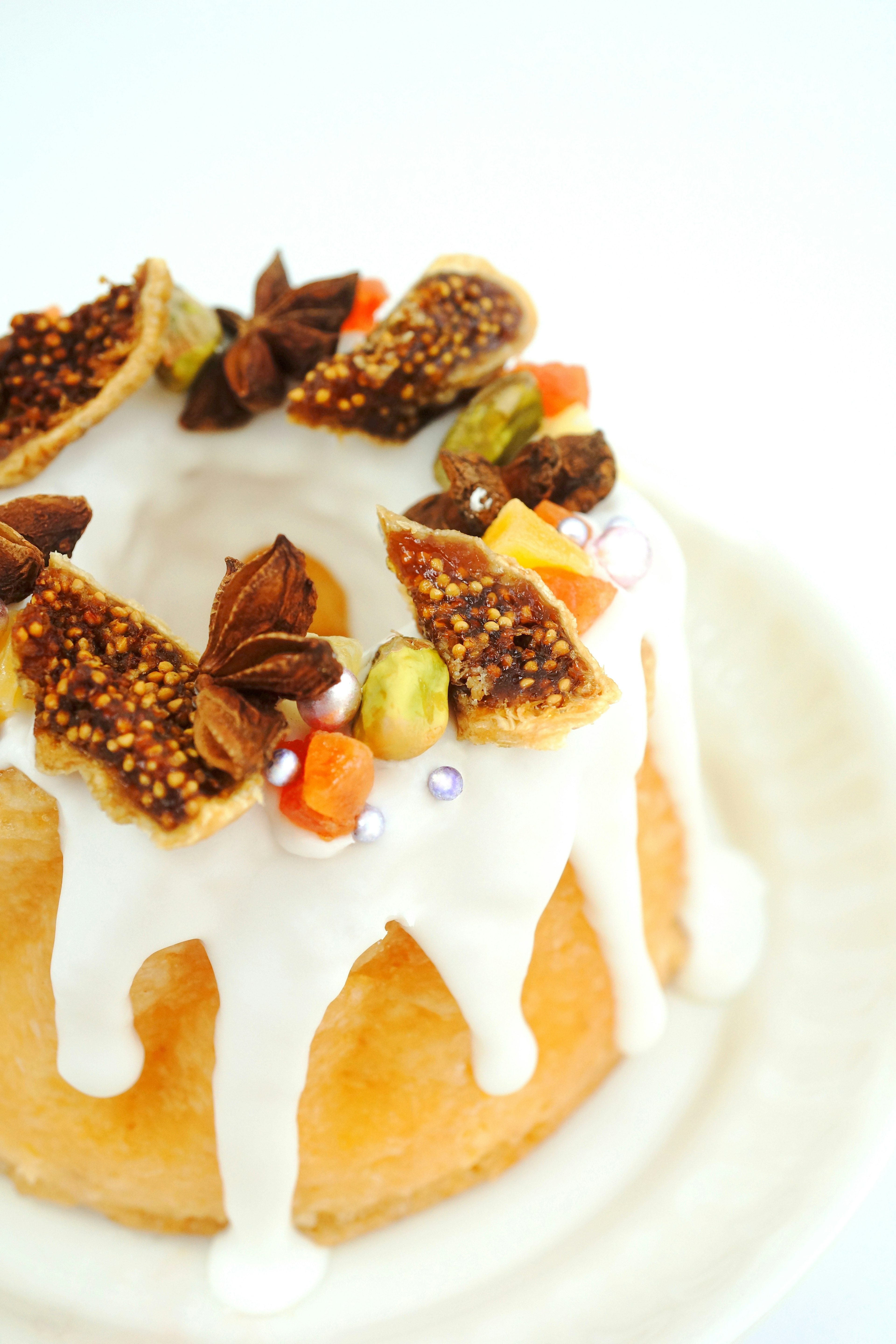 Un dessert con una torta ricoperta di glassa bianca e guarnita con noci e frutta secca