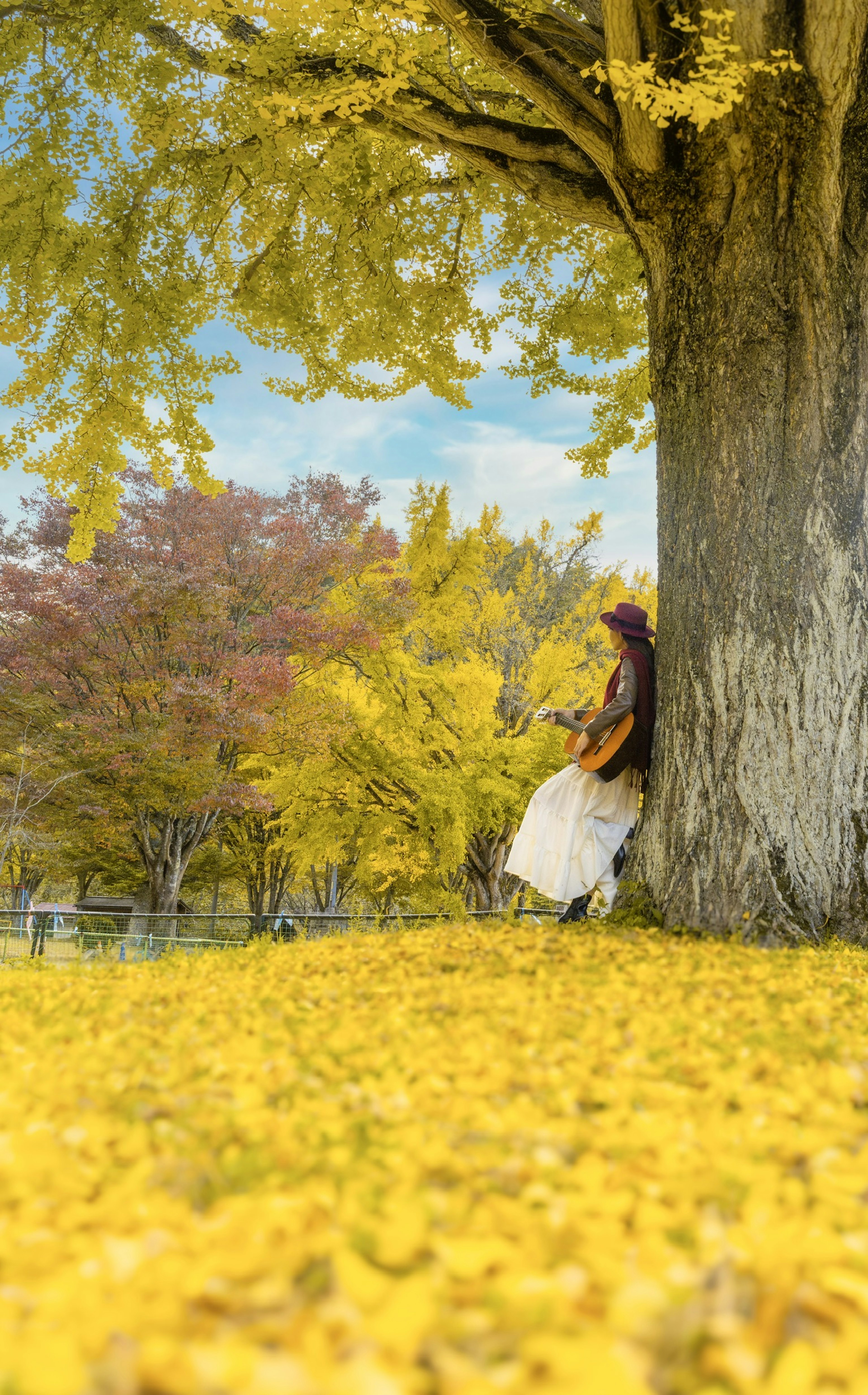 Eine Frau lehnt an einem großen Baum in einer herbstlichen Landschaft