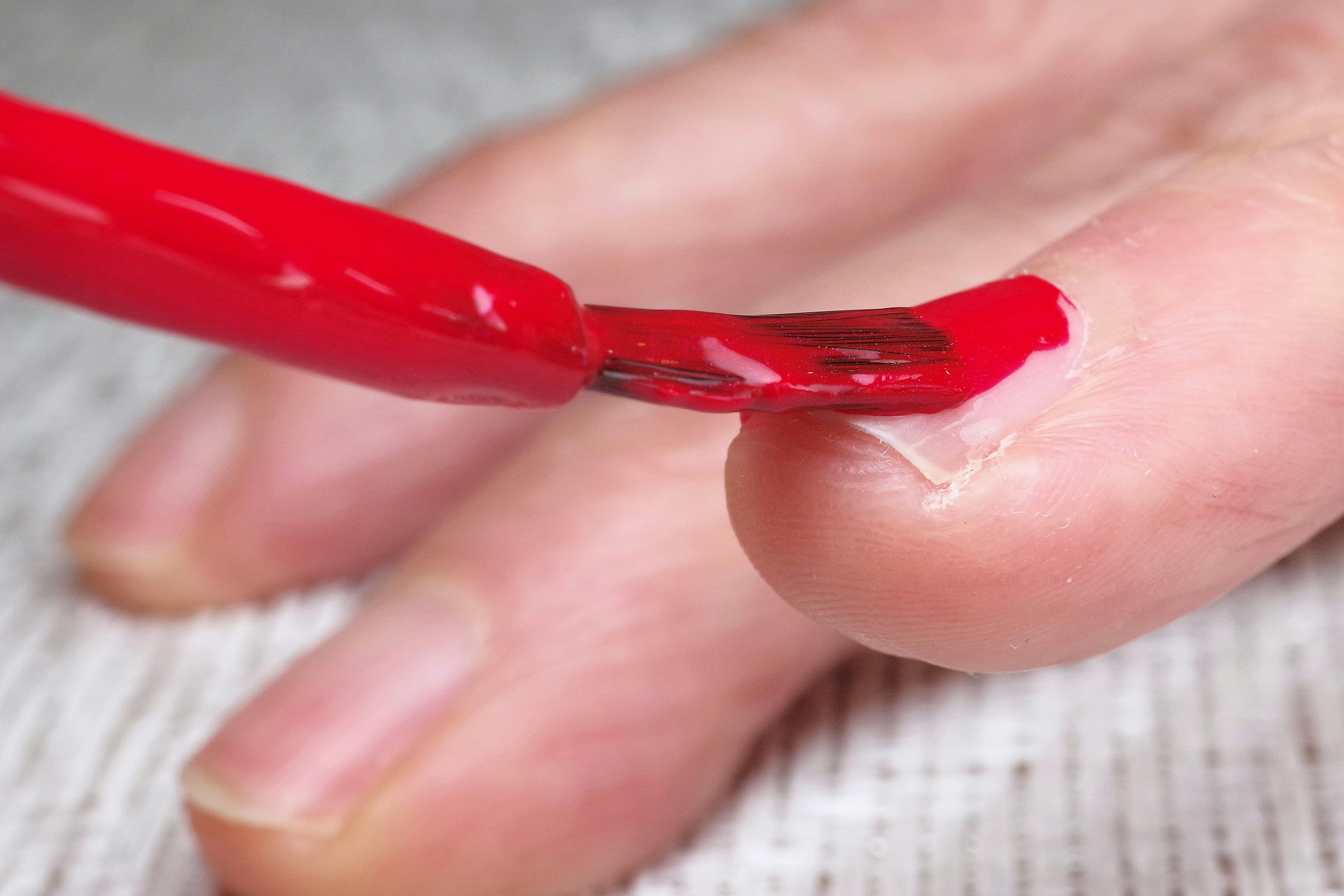 Aplicando esmalte de uñas rojo en un dedo