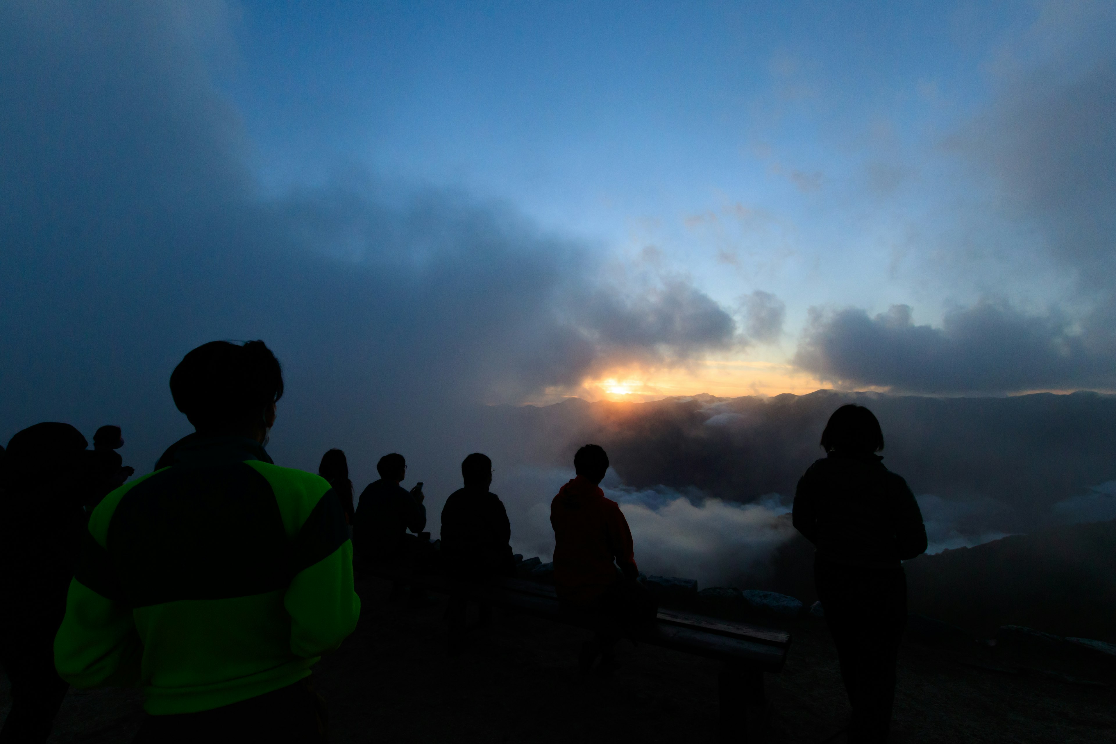 Silhouette von Personen, die im Nebel auf den Sonnenaufgang warten