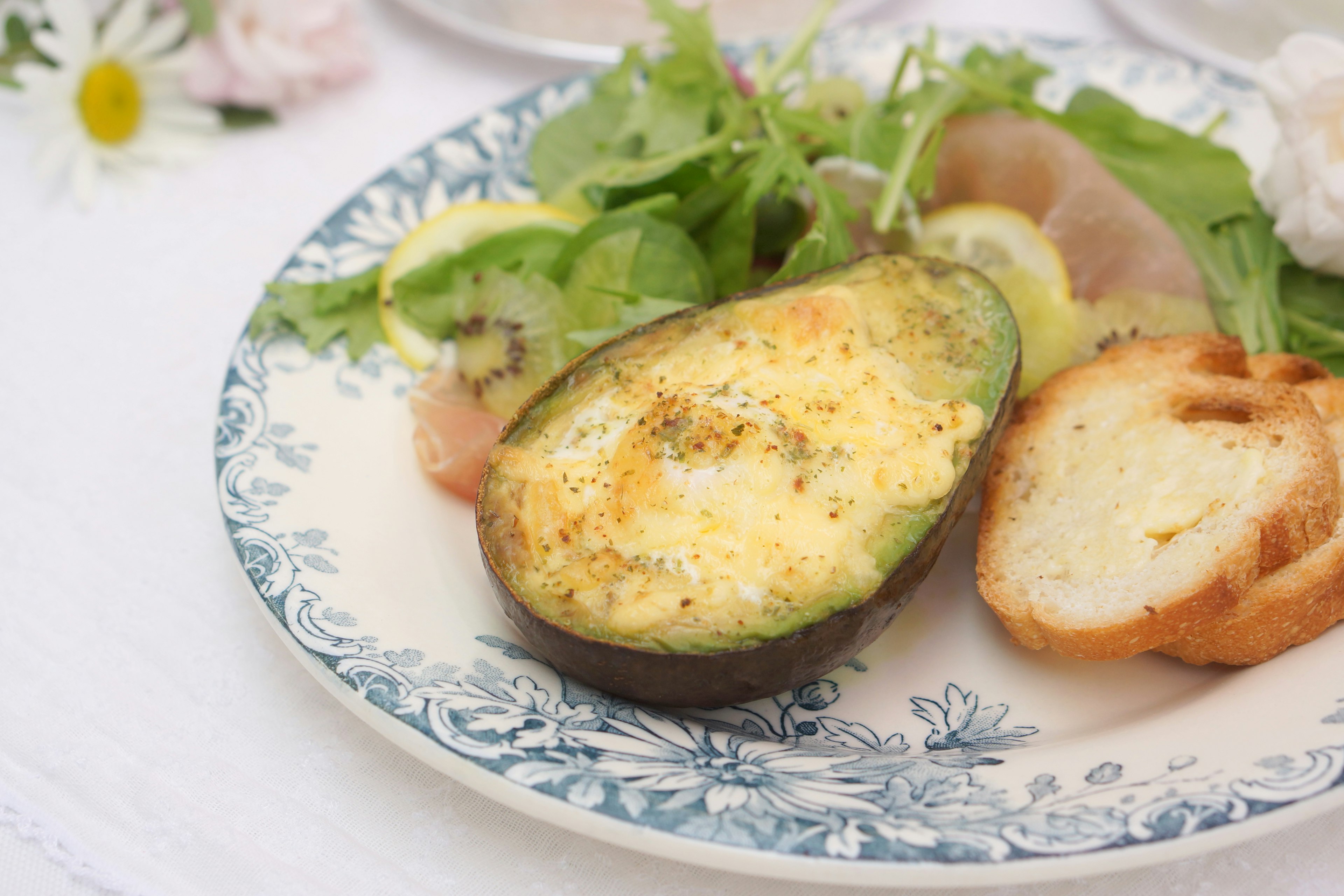 Aguacate al horno con ensalada y pan crujiente en un plato decorativo