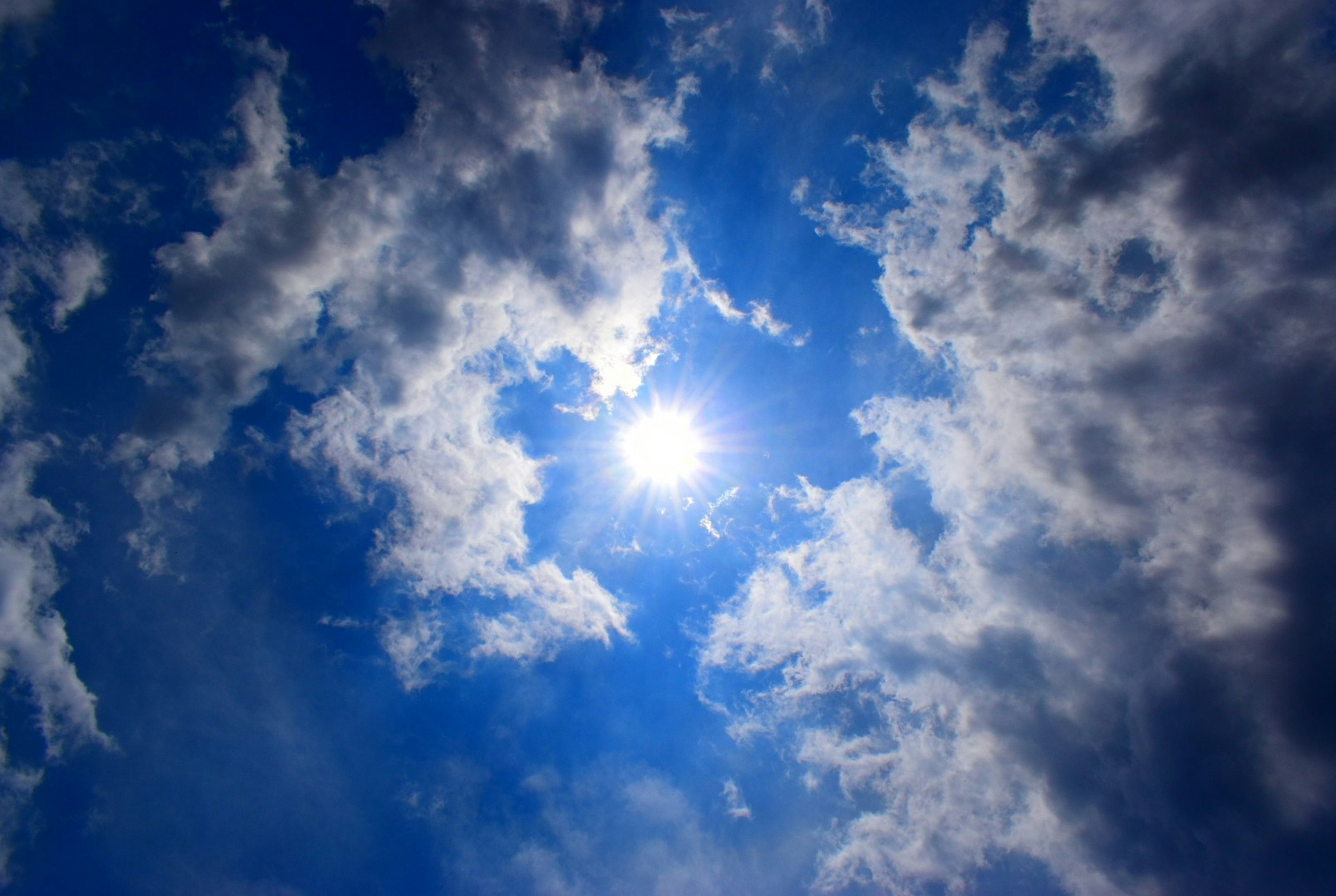 Helle Sonne, die durch weiße Wolken in einem blauen Himmel scheint