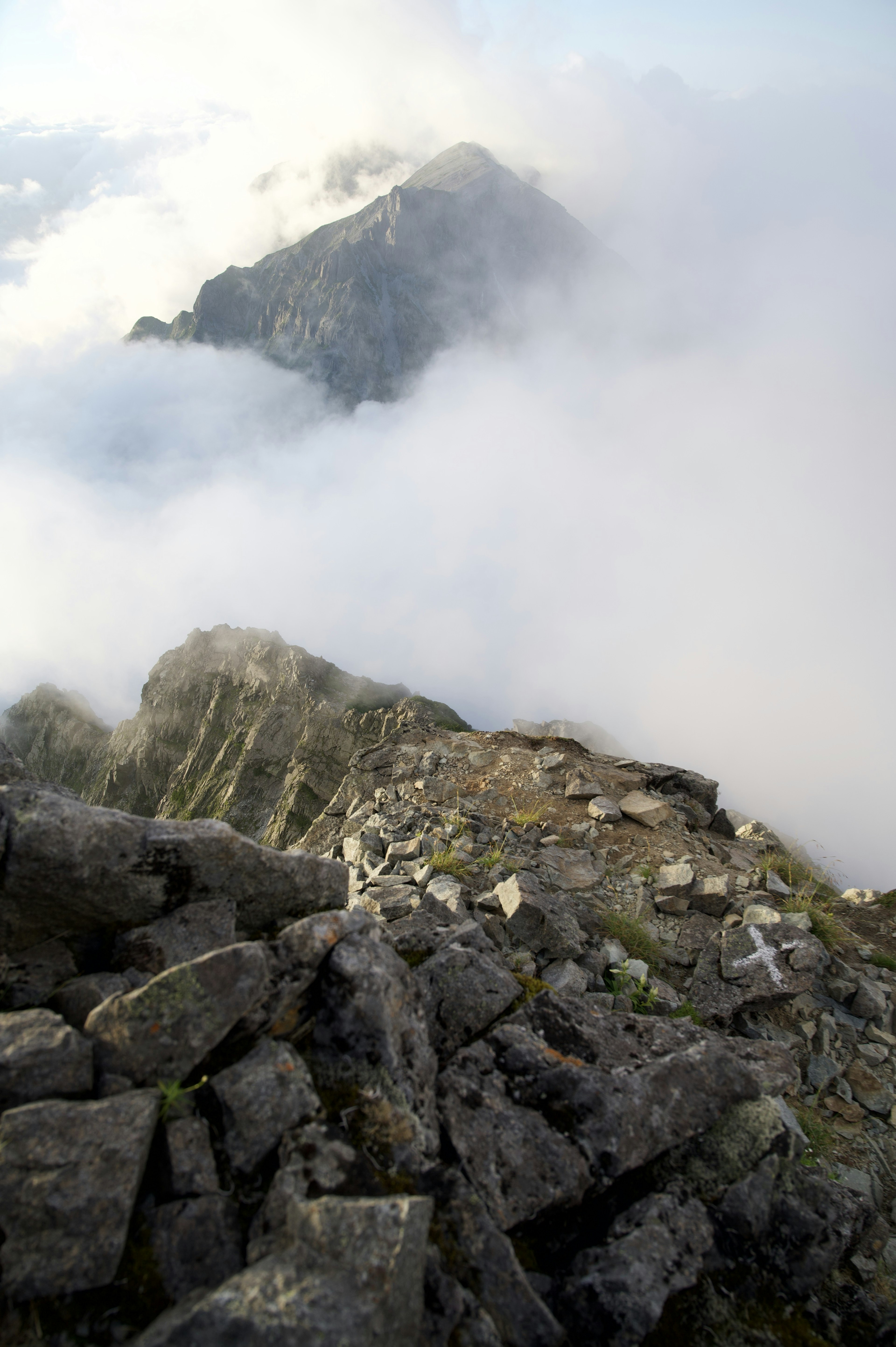 Picco di montagna avvolto nelle nuvole con terreno roccioso