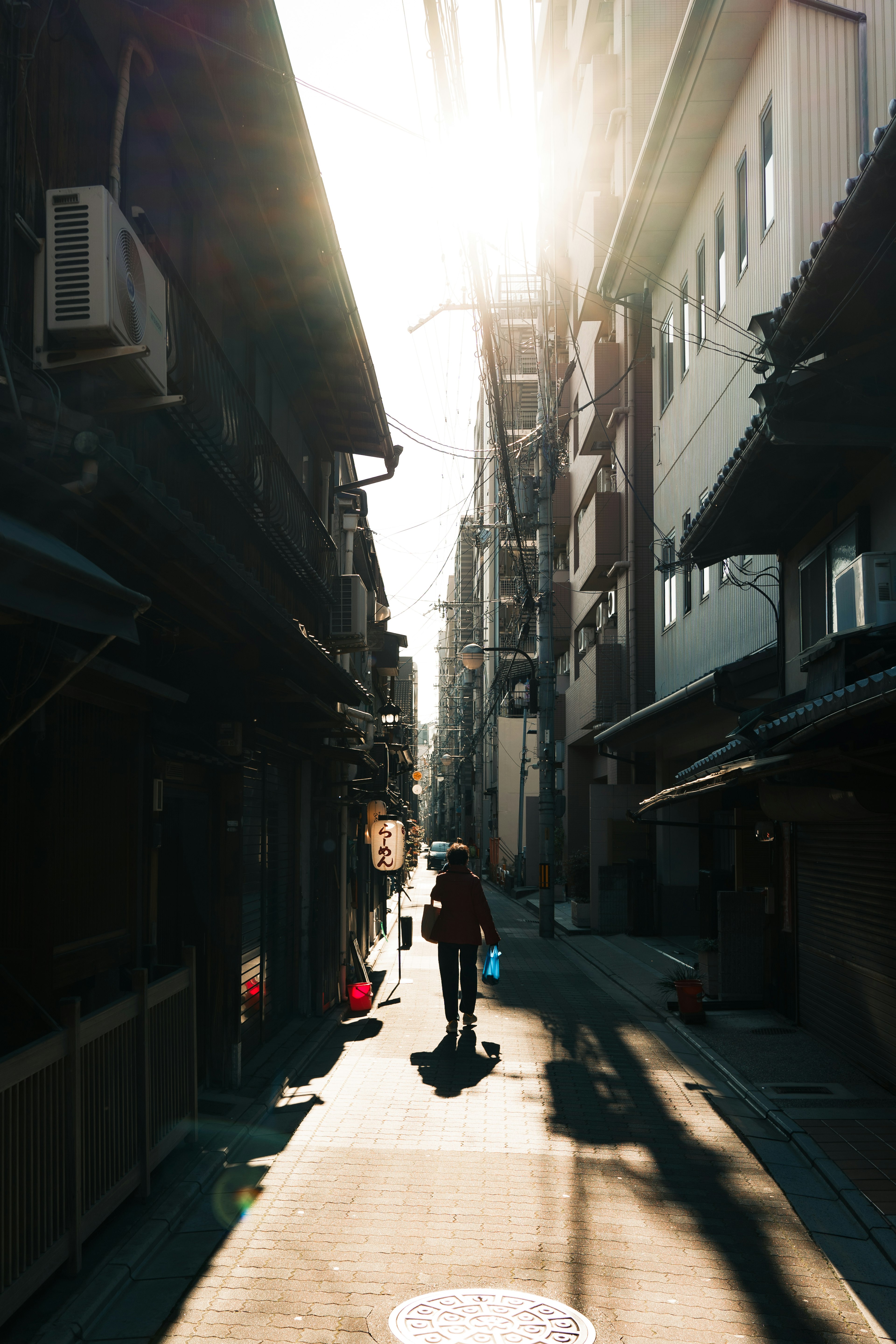 Silhouette einer Person, die in einer engen Gasse mit Sonnenlicht geht