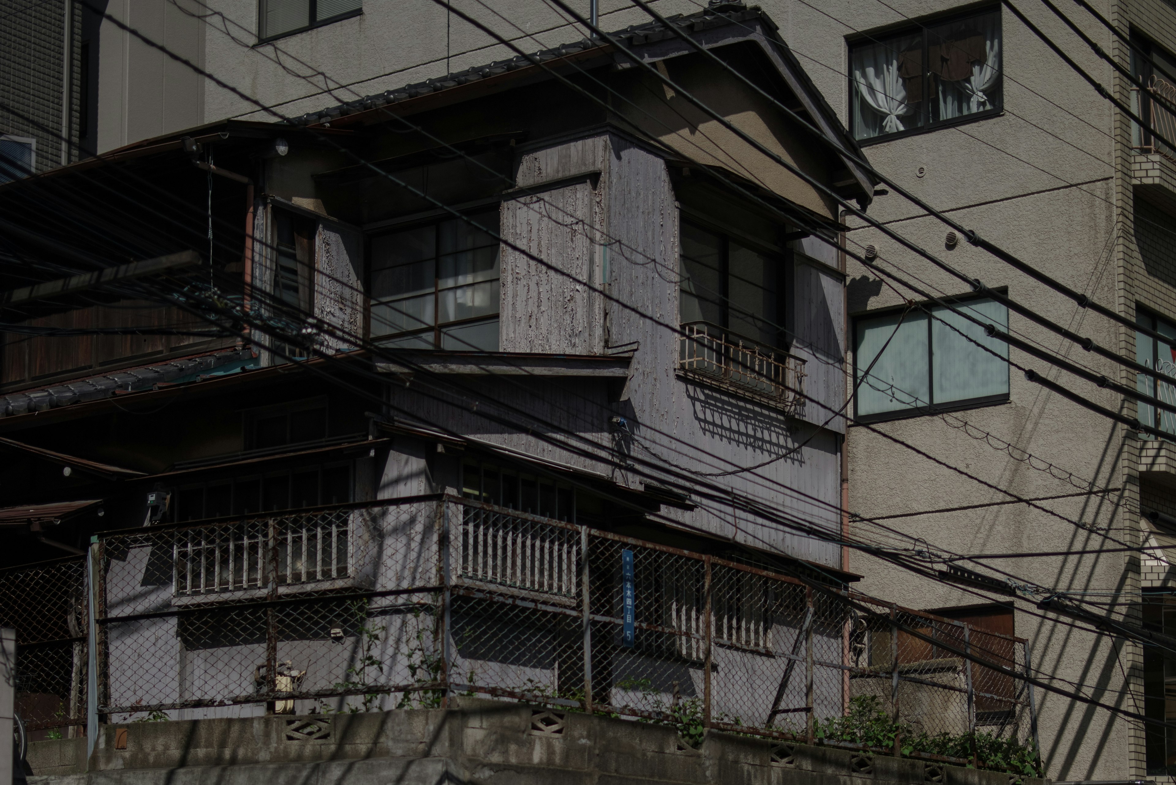 An old Japanese house with modern buildings and tangled wires