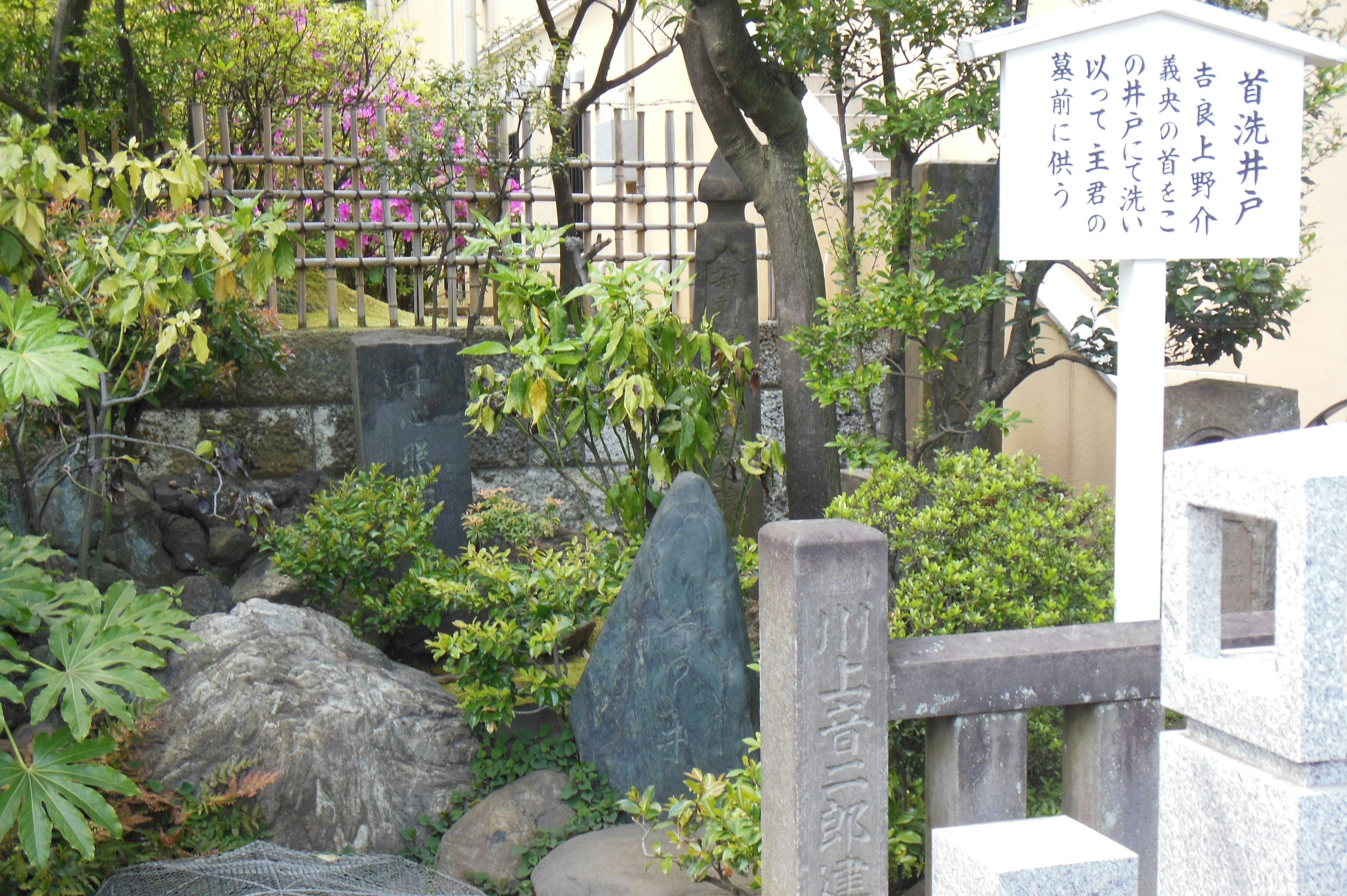 A lush Japanese garden with rocks and greenery featuring a nearby informational sign