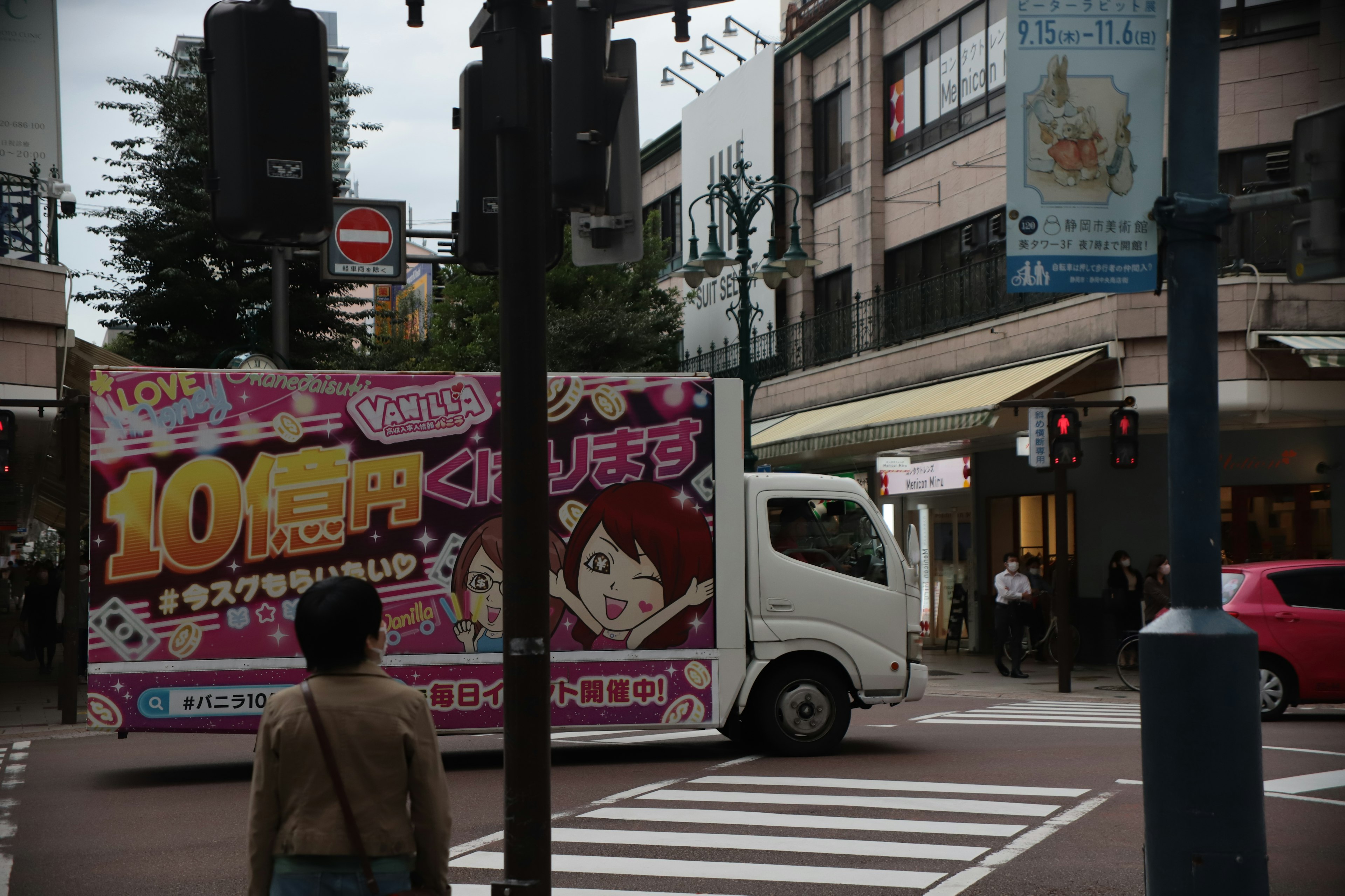 Intersection animée dans une zone commerciale avec un camion publicitaire rose en vedette