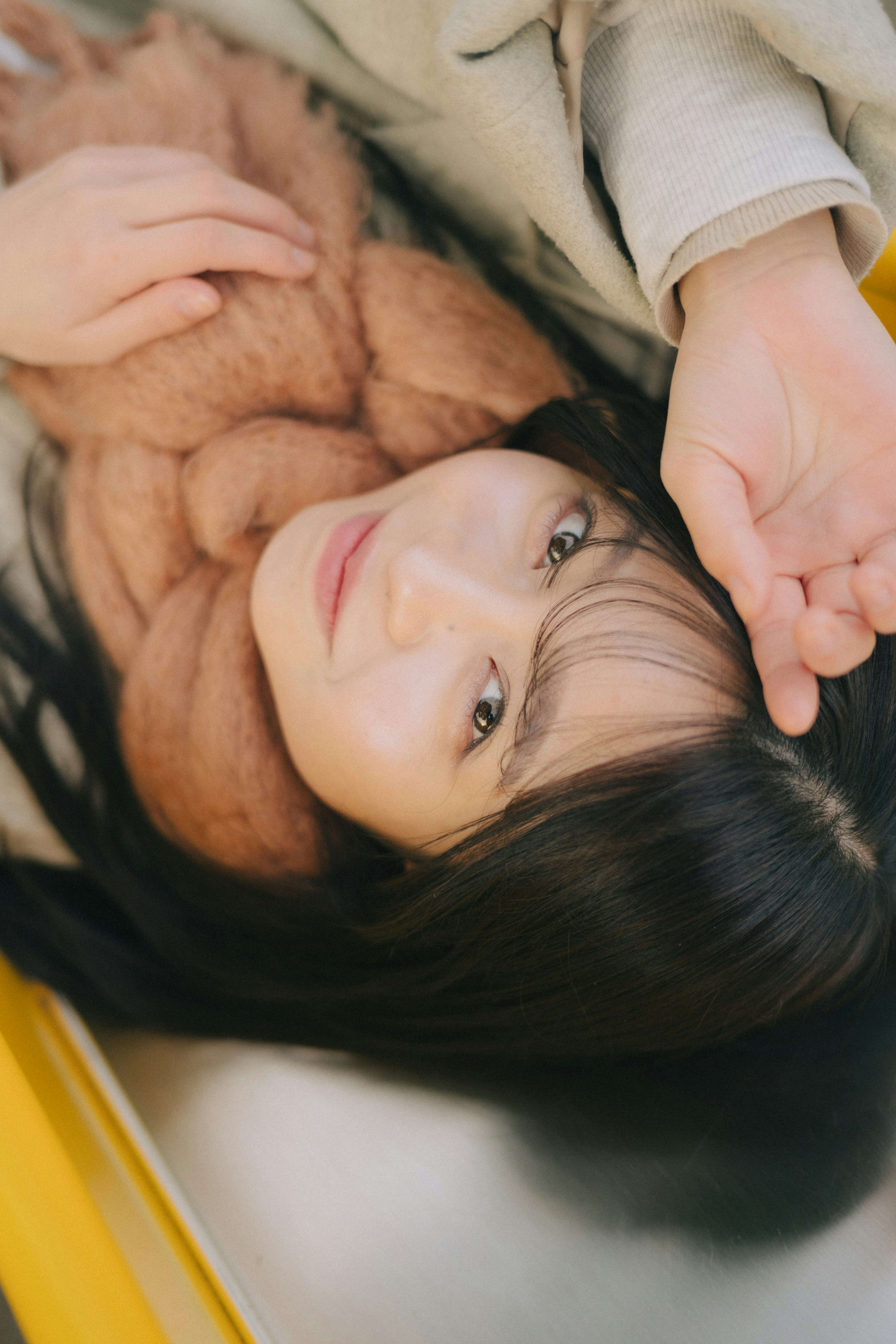 Una mujer acostada envuelta en una bufanda con cabello oscuro largo