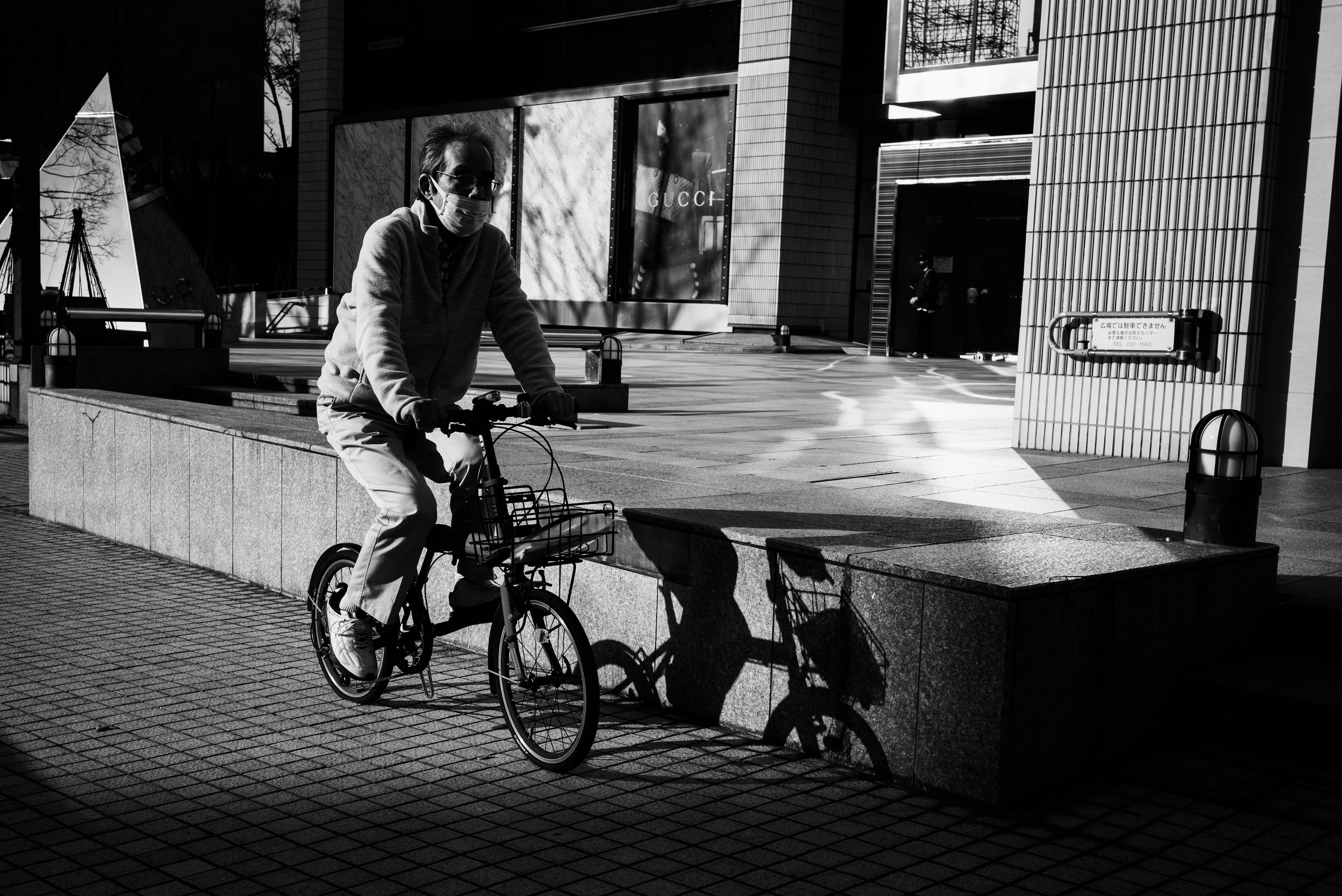 A man riding a bicycle in a black and white urban setting