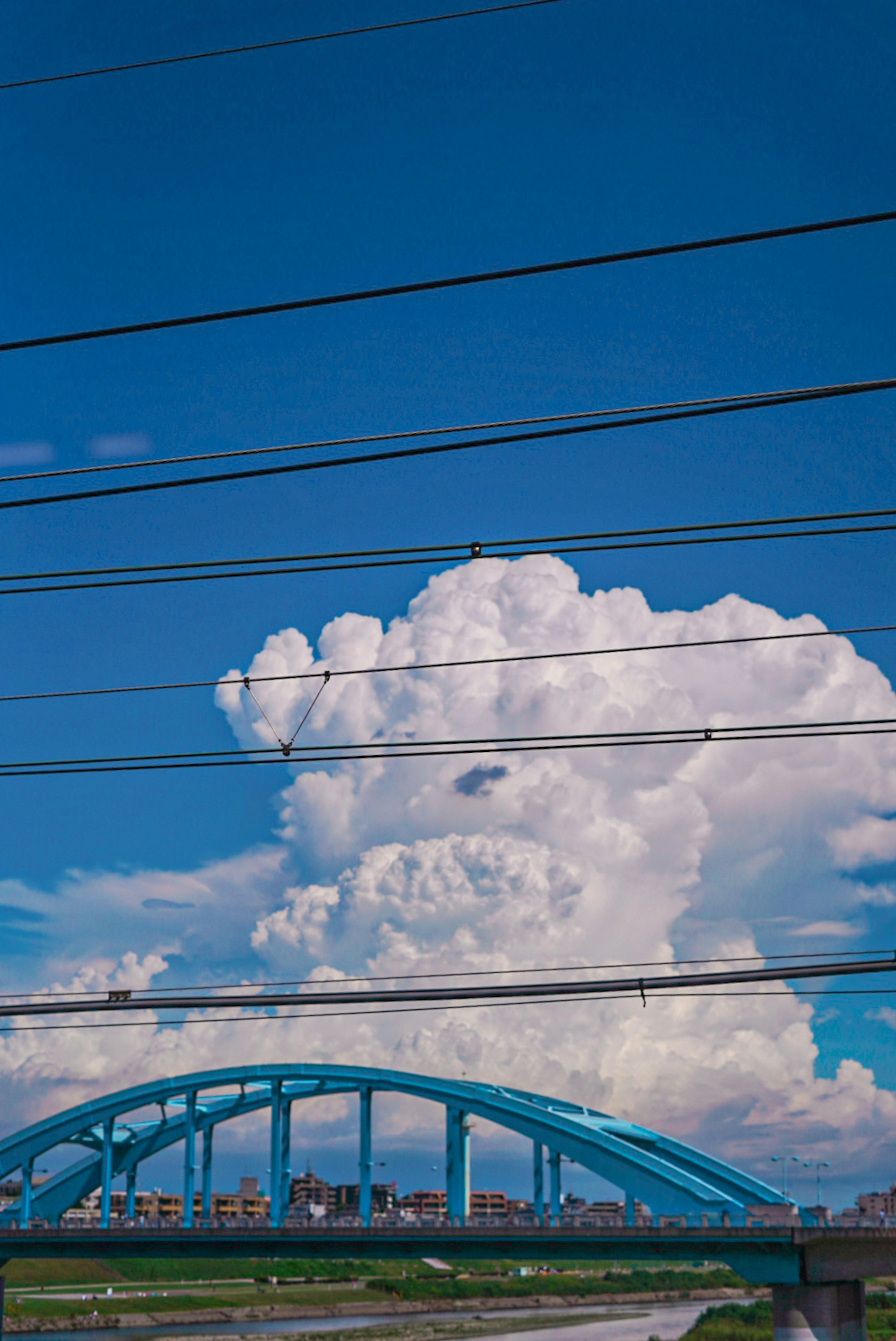 Pont bleu sous un ciel lumineux avec des nuages blancs duveteux