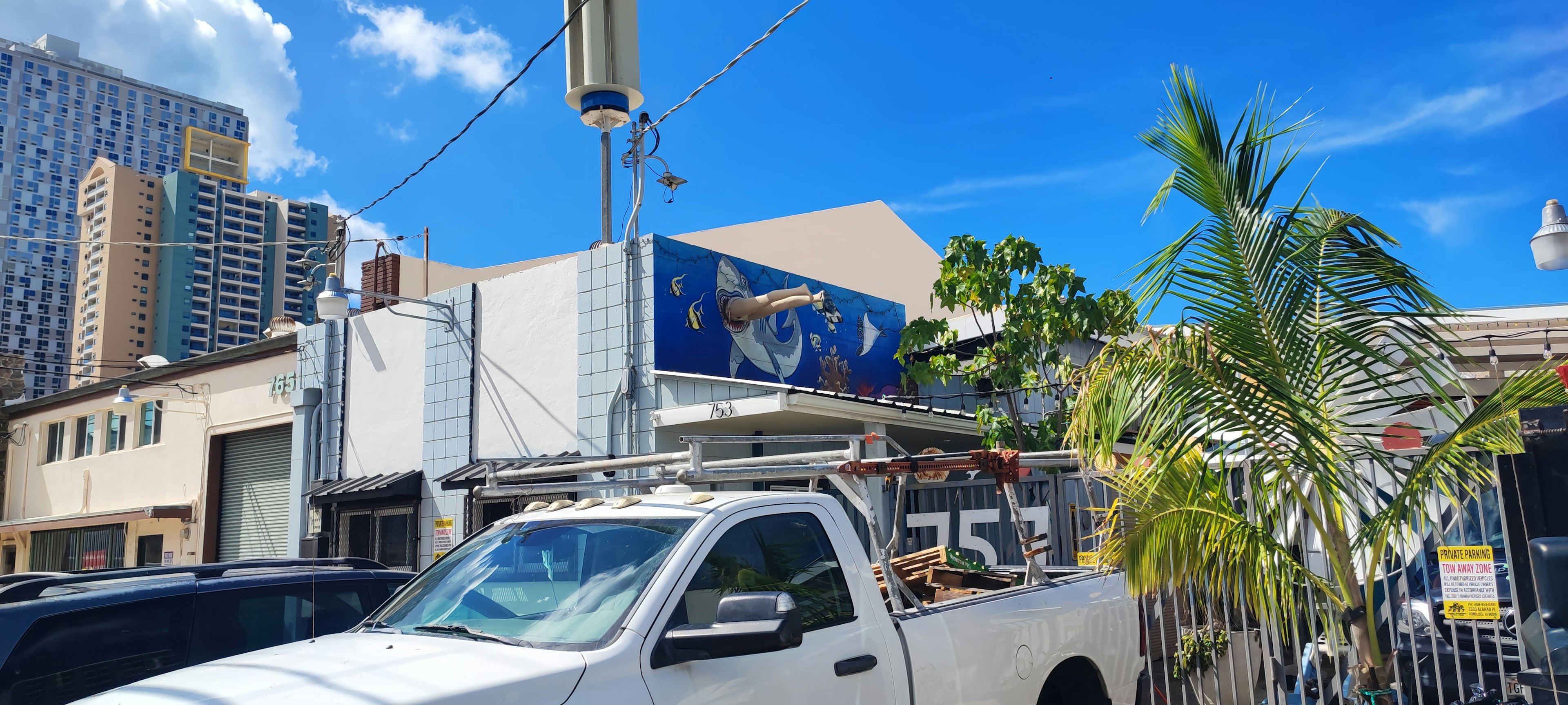 Un camion bianco parcheggiato in un contesto urbano con cielo blu e edifici sullo sfondo