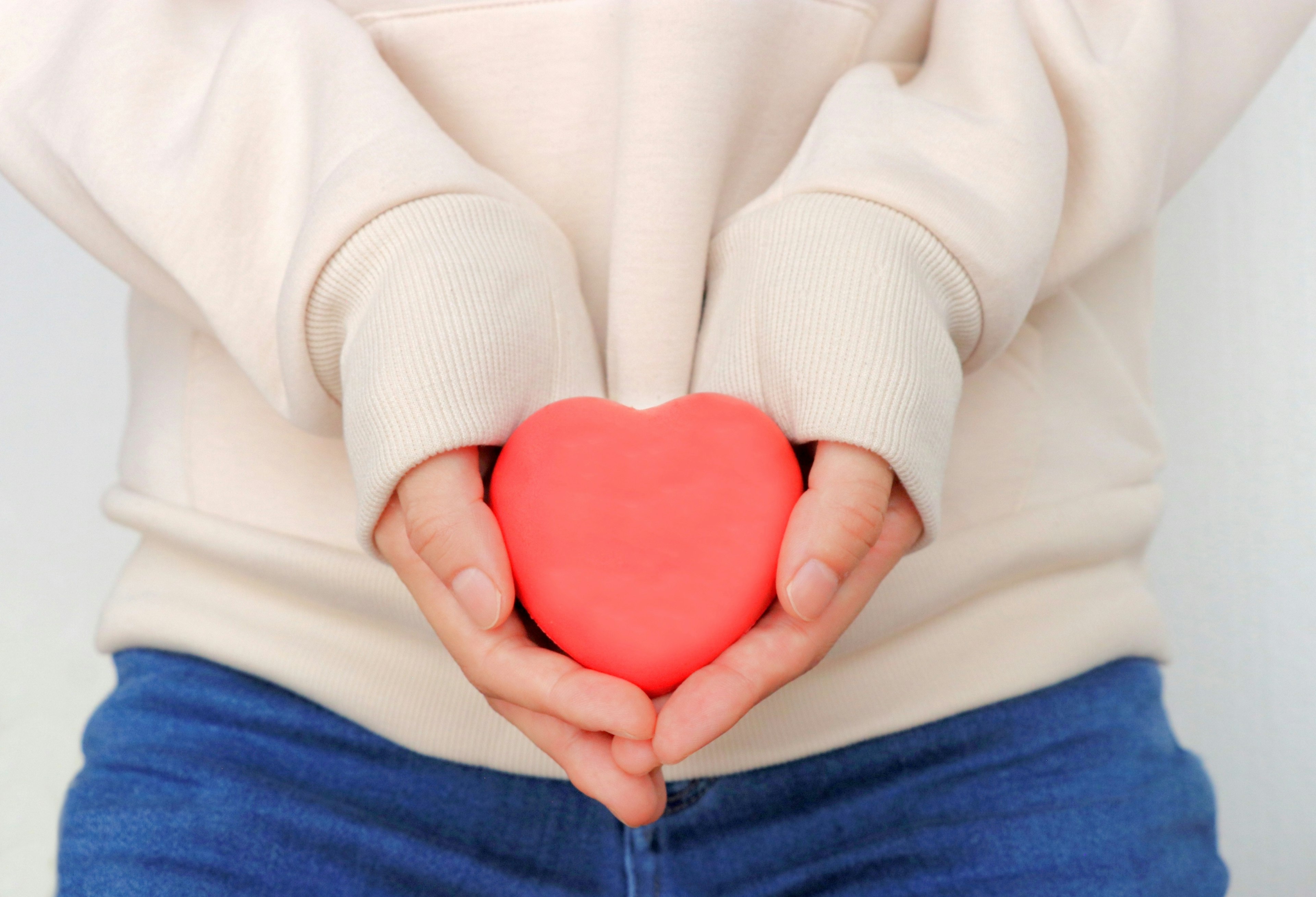 Mani che tengono un oggetto a forma di cuore rosso