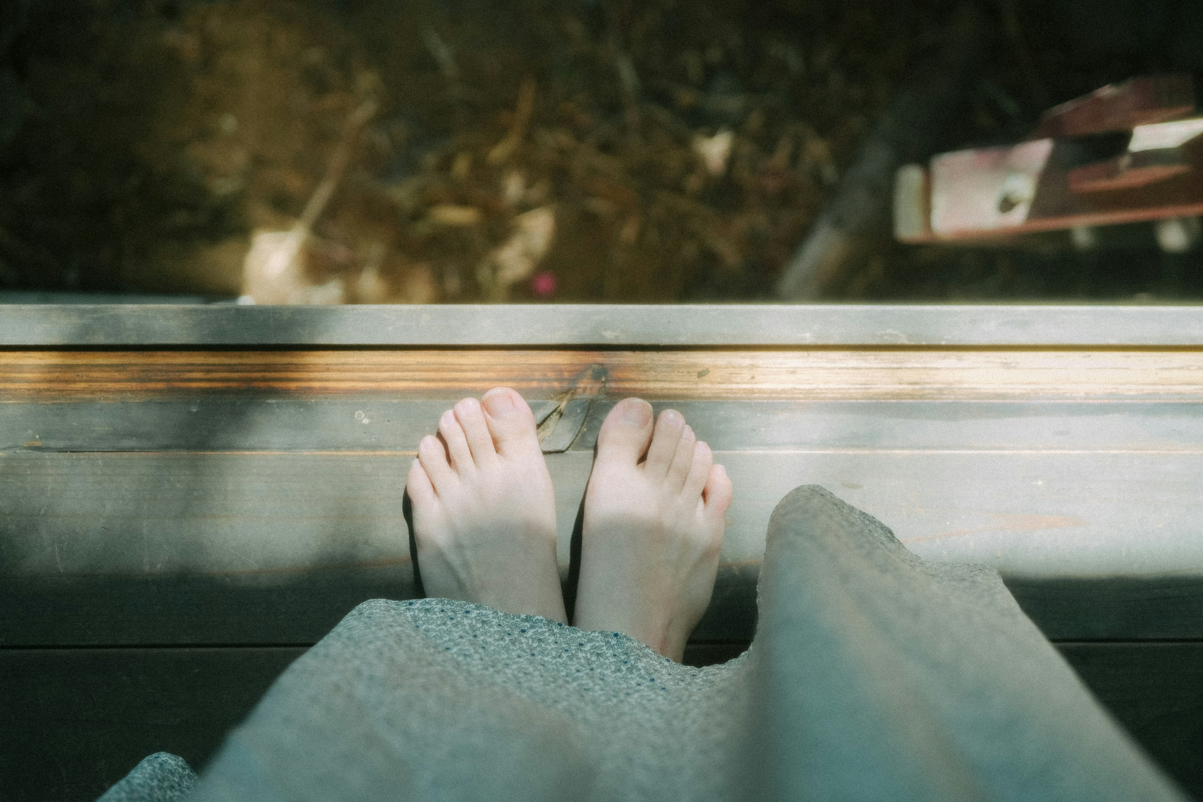 A photo of bare feet standing on a wooden floor with a soft focus background