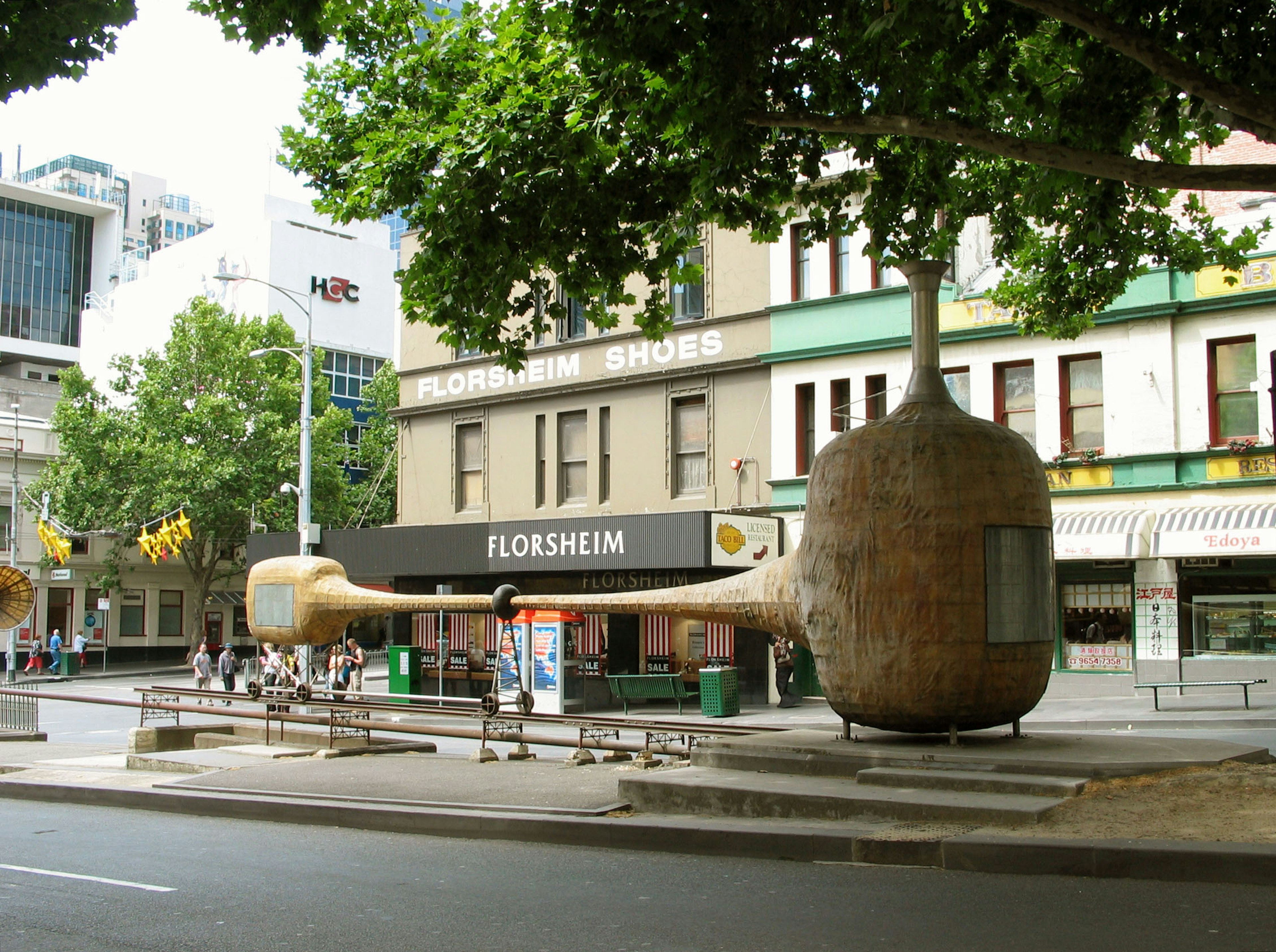 Unique shoe sculpture on city street with surrounding buildings