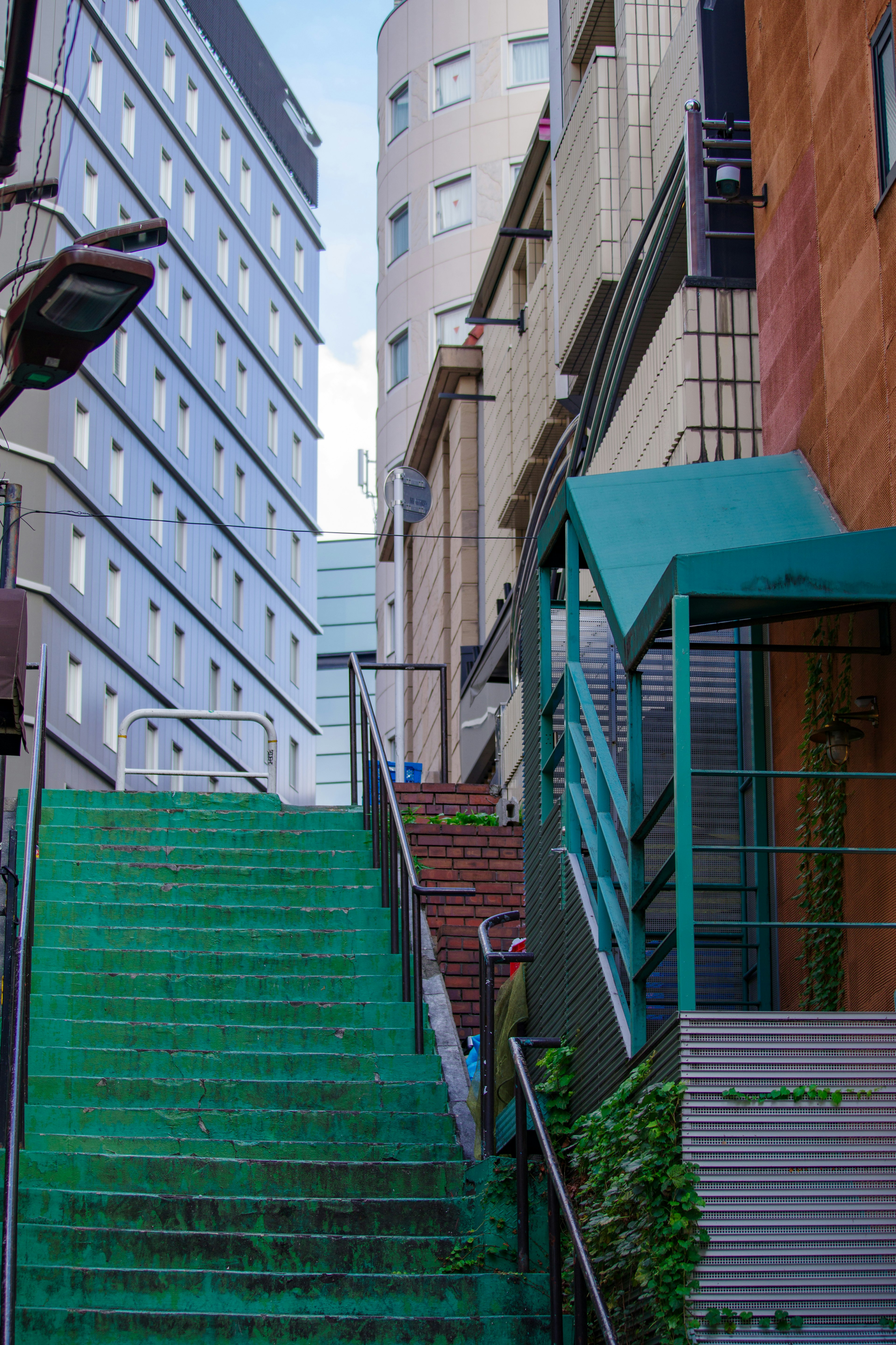 Green staircase leading up between modern buildings