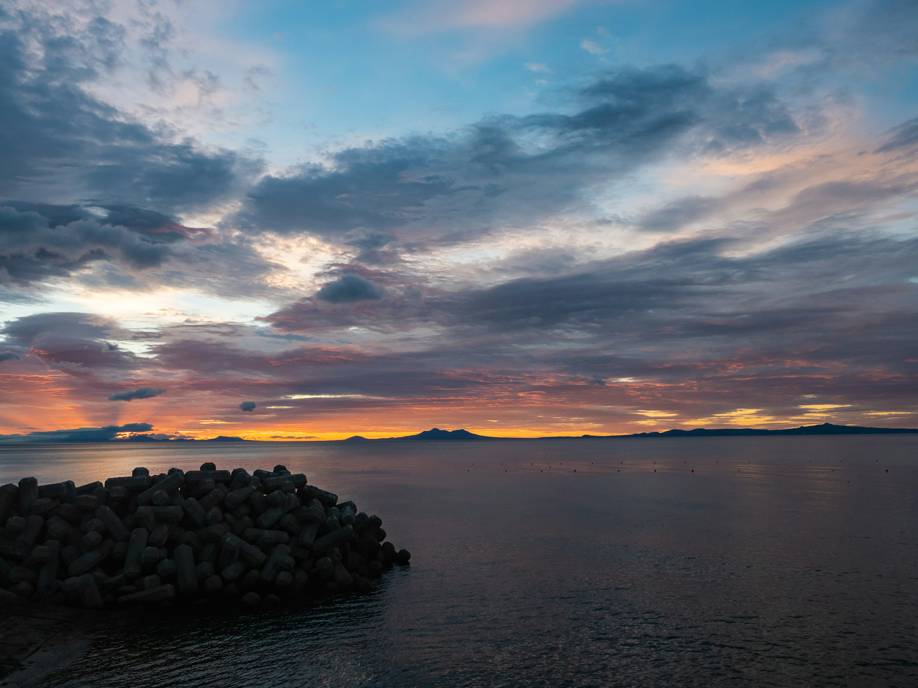 Atardecer sobre el océano con un rompeolas de rocas