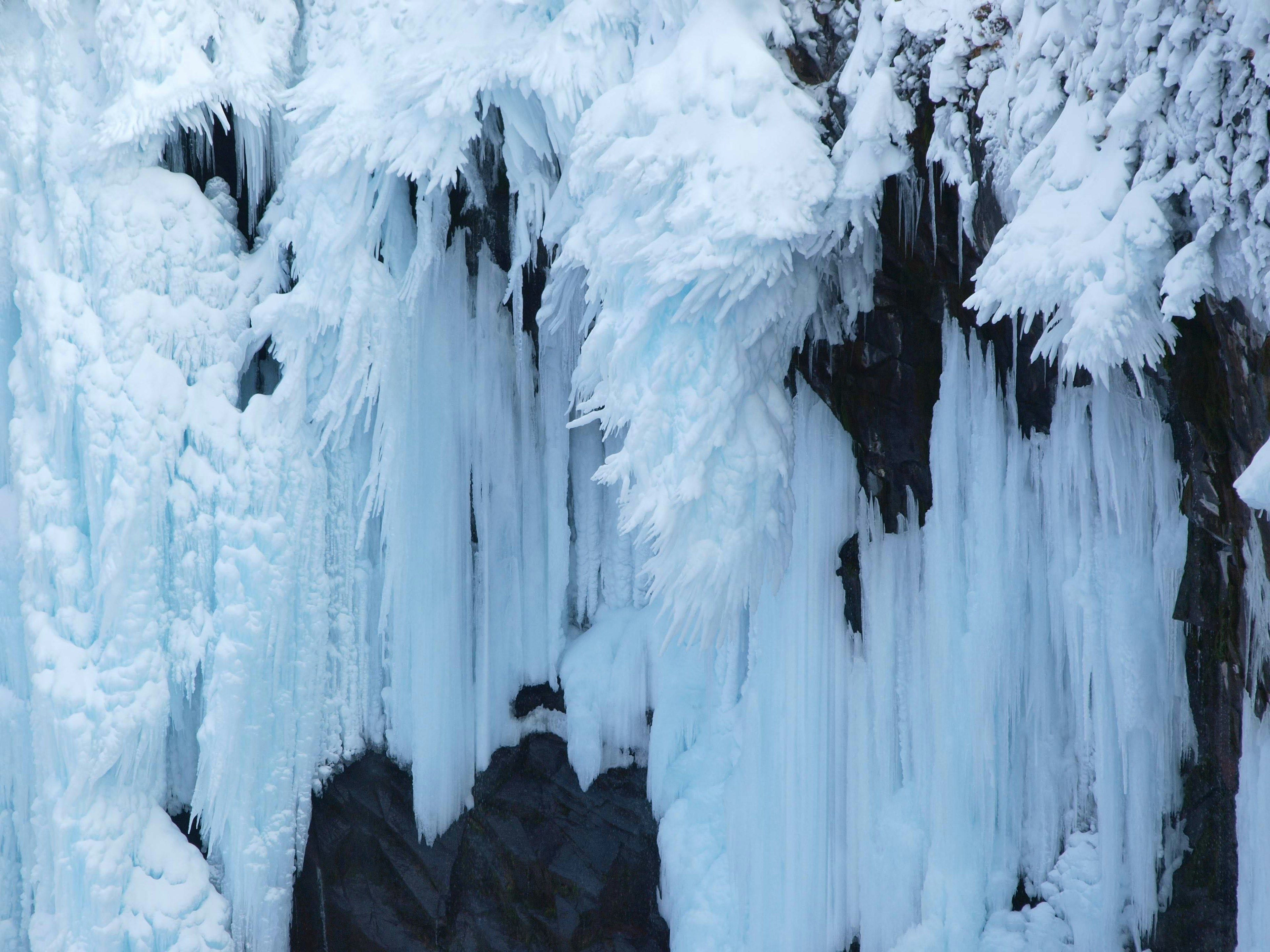 Primer plano de una cascada de hielo con capas de hielo sobre rocas oscuras