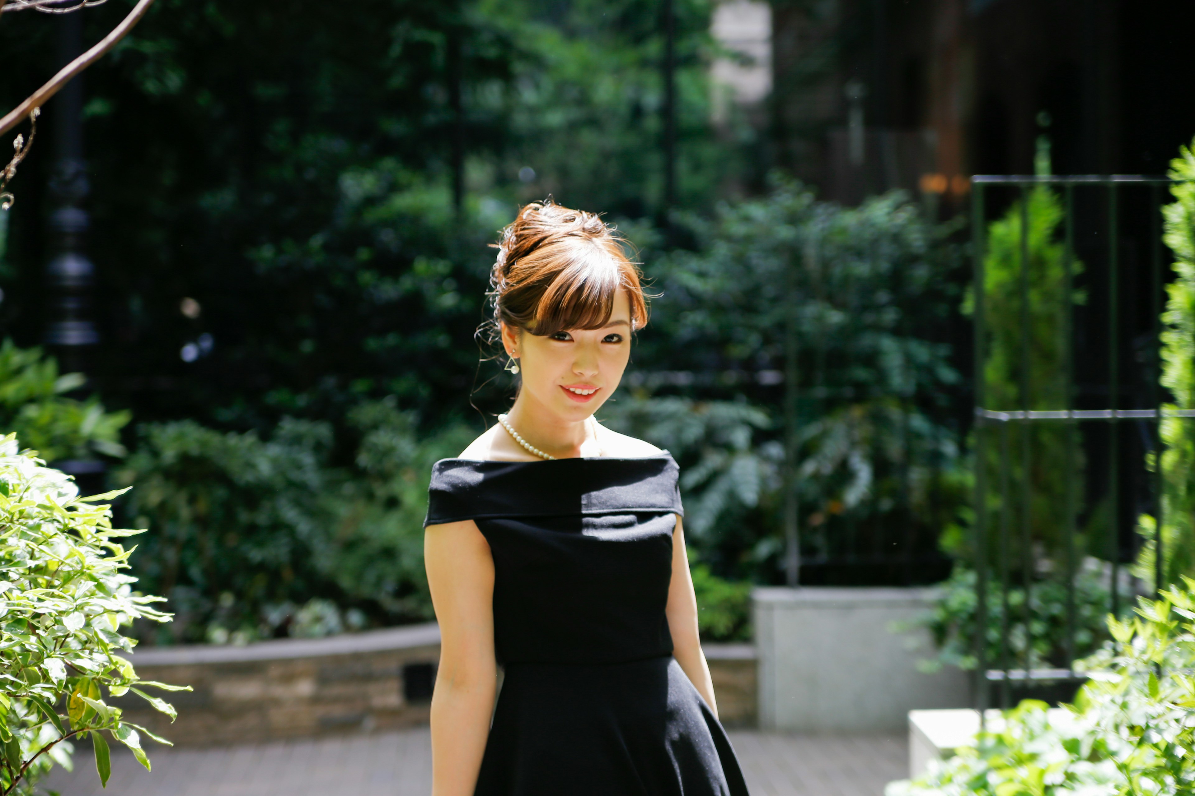 Femme en robe noire se tenant dans un jardin vert