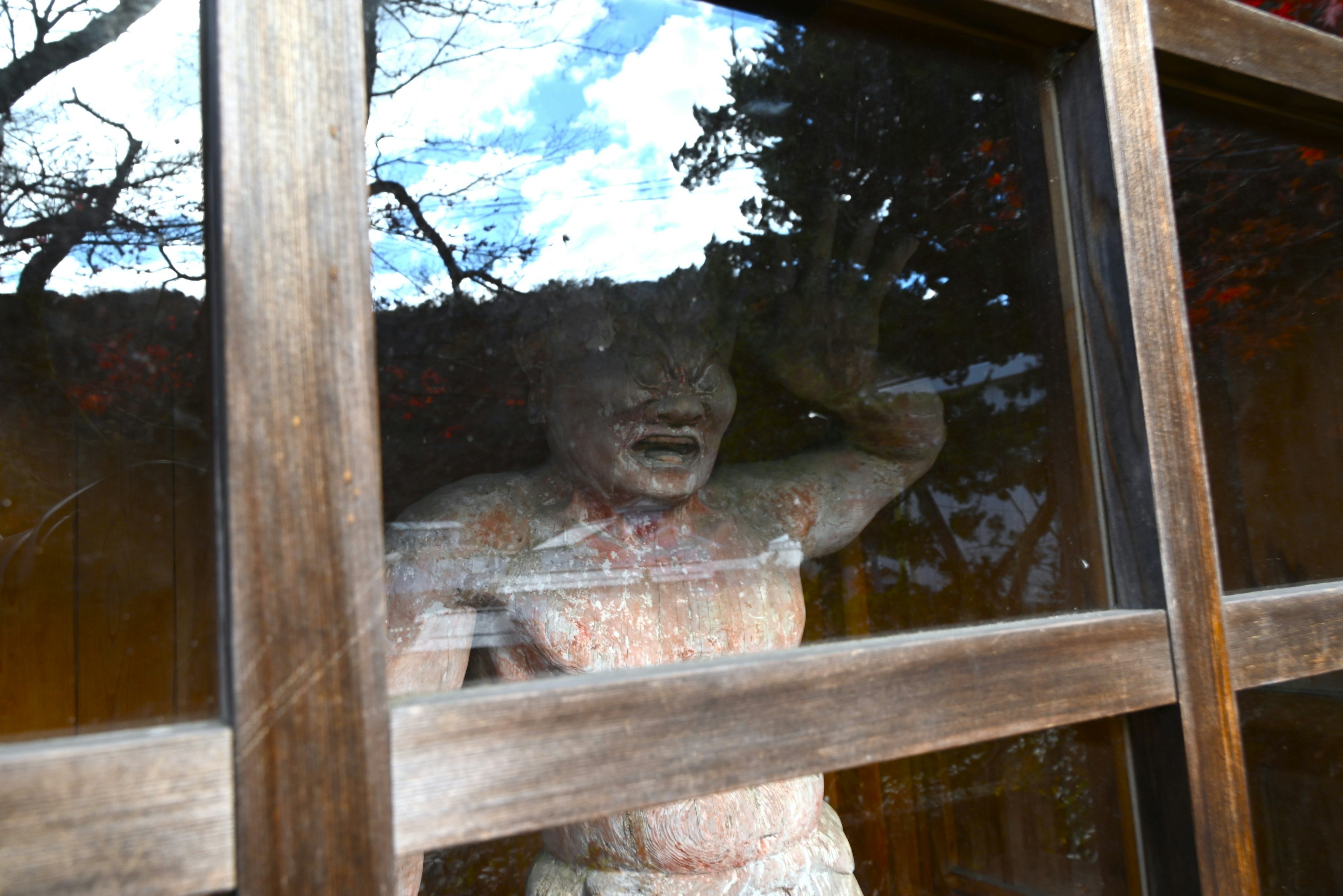 Statue derrière une fenêtre en bois avec expression faciale