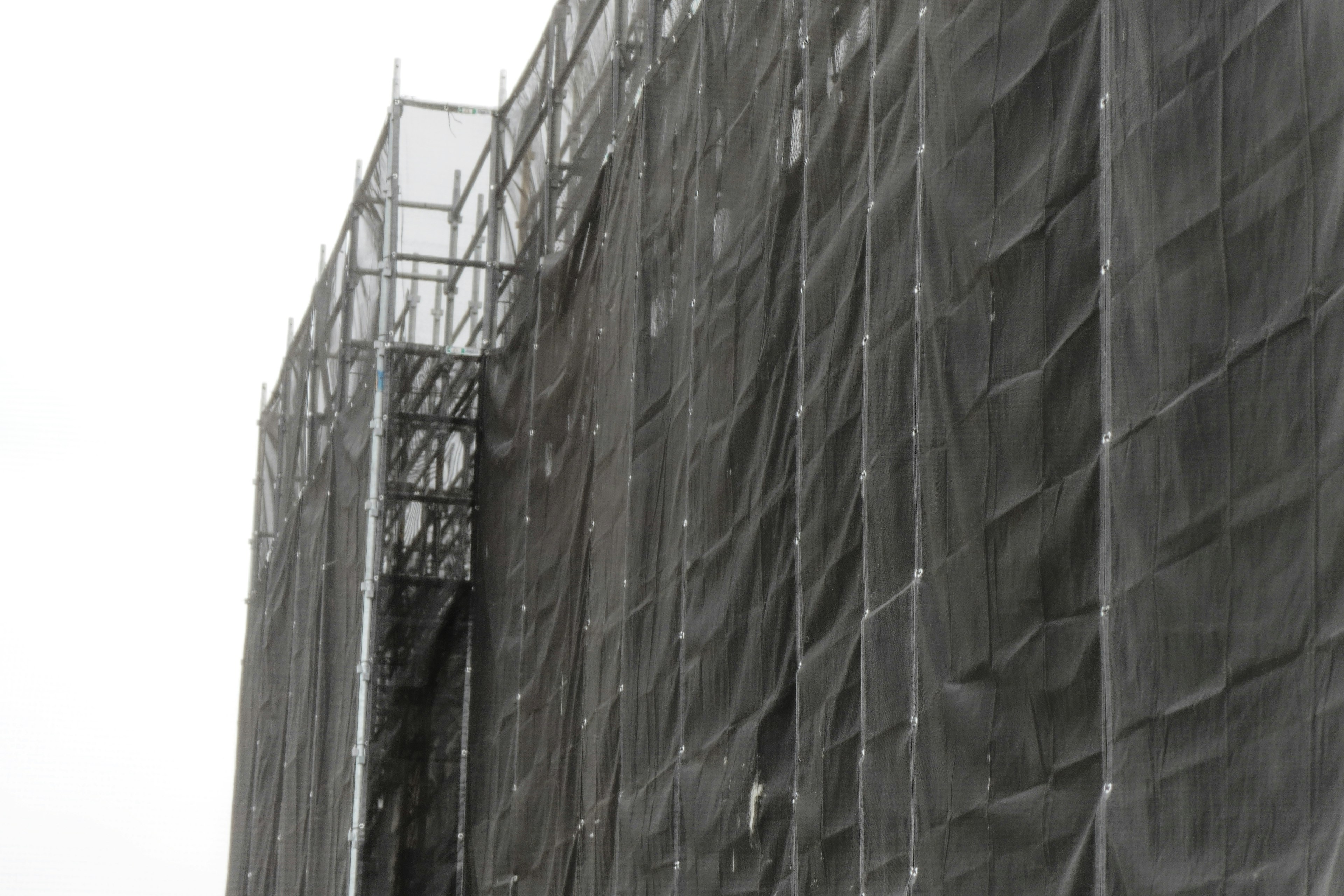 Construction site with black netting covering a building facade and scaffolding