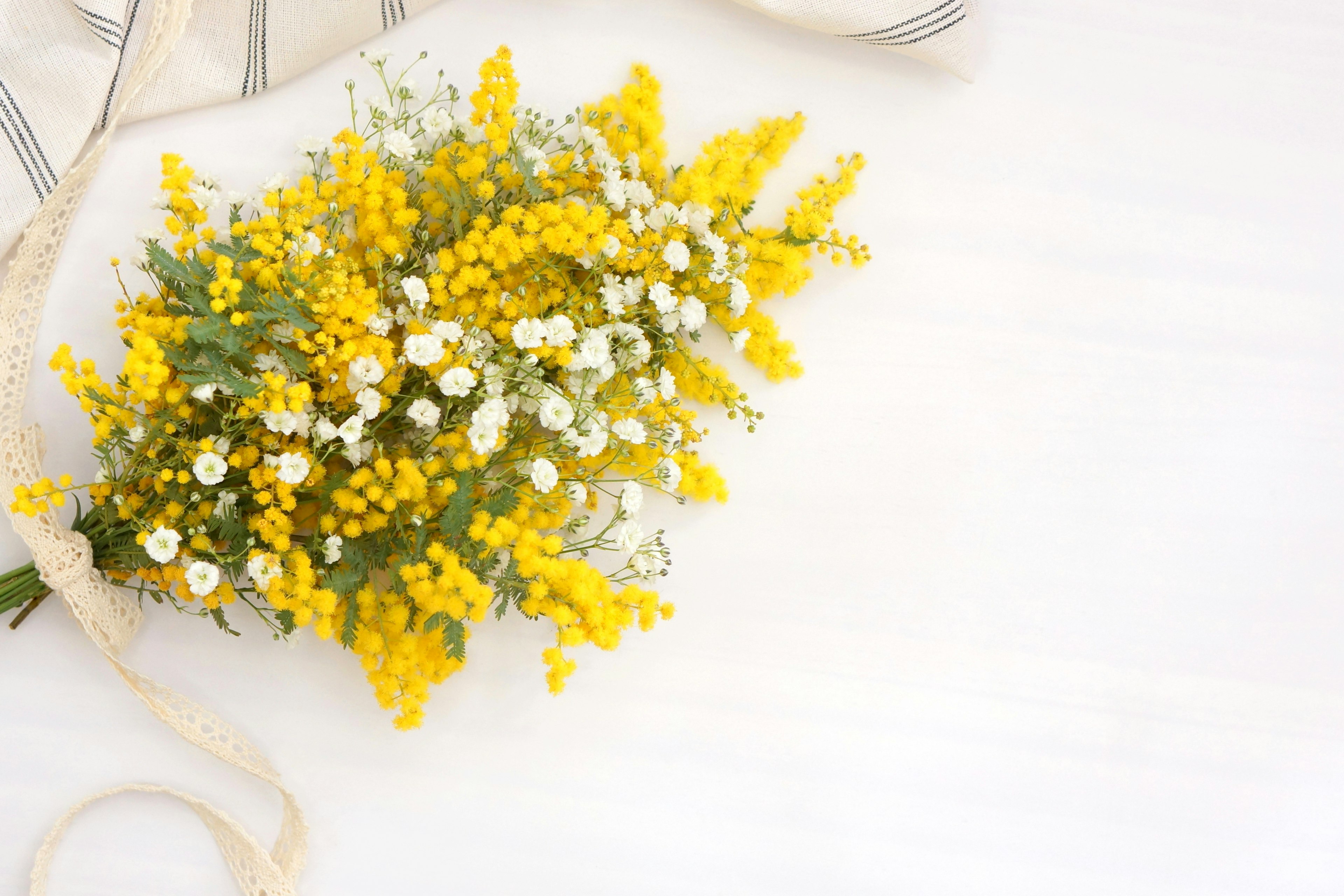 A bouquet of yellow mimosa and white flowers arranged on a table