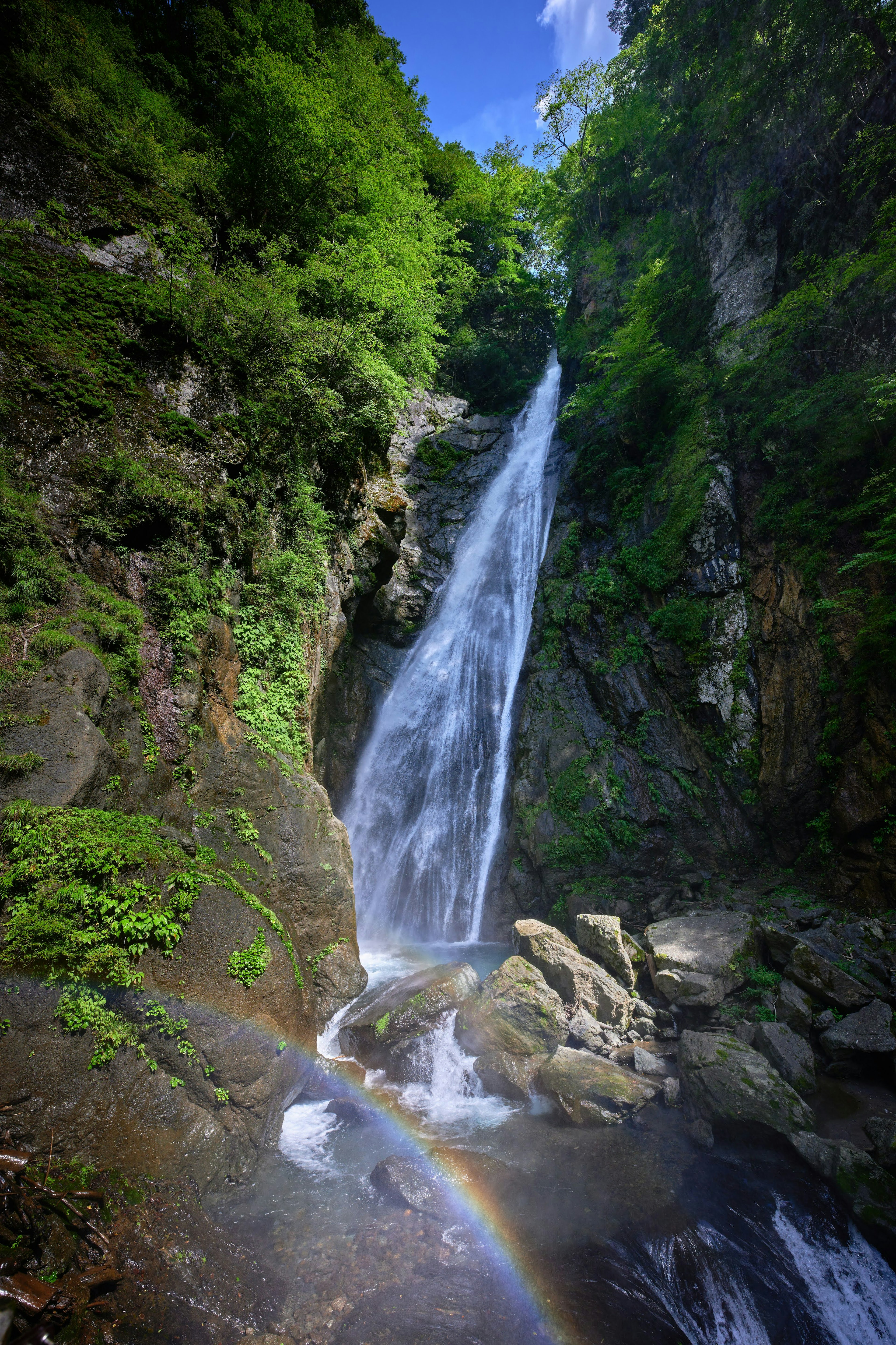 Sebuah air terjun indah mengalir melalui pegunungan hijau