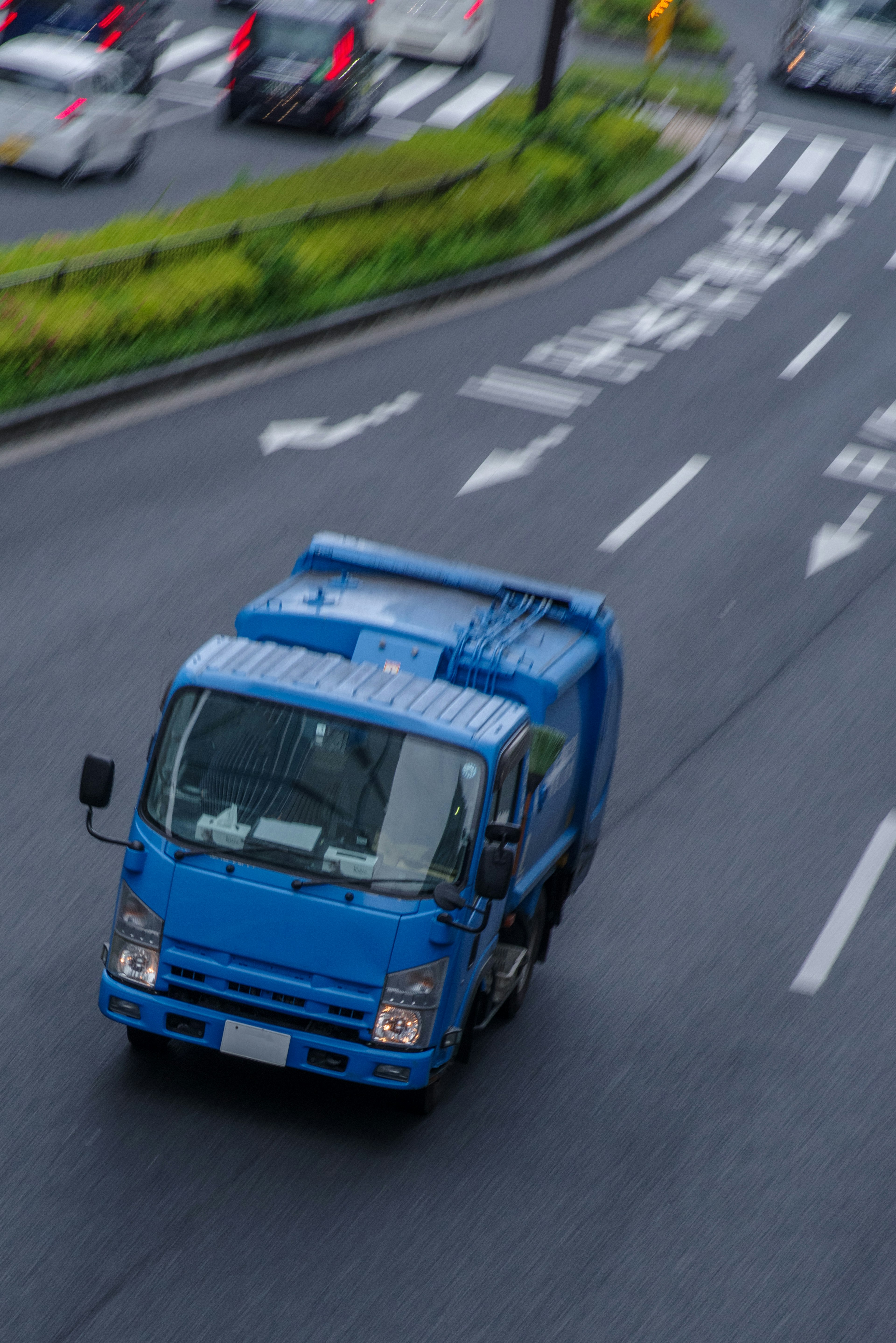 A blue truck driving on the road with other vehicles in the background