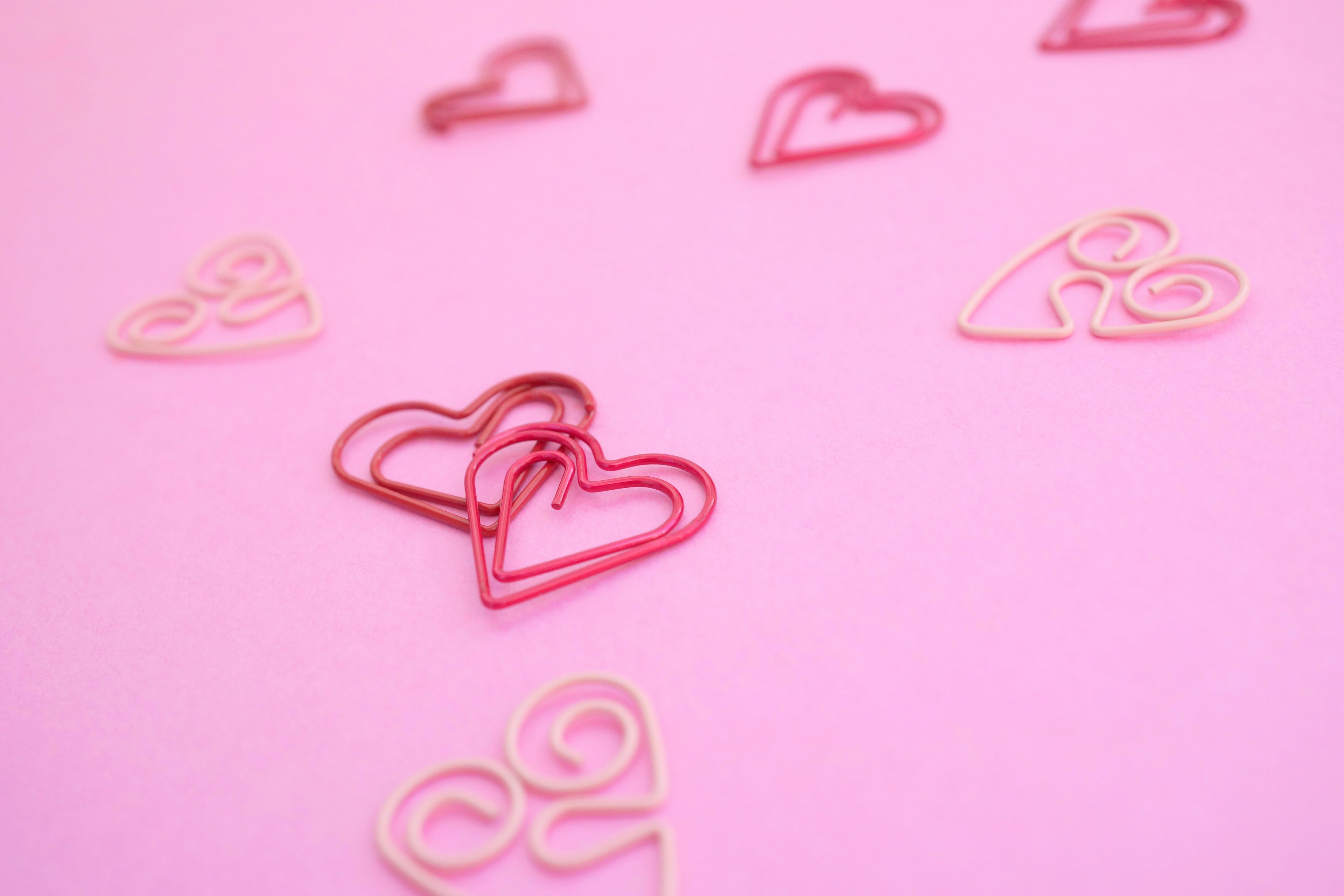 Heart-shaped clips scattered on a pink background