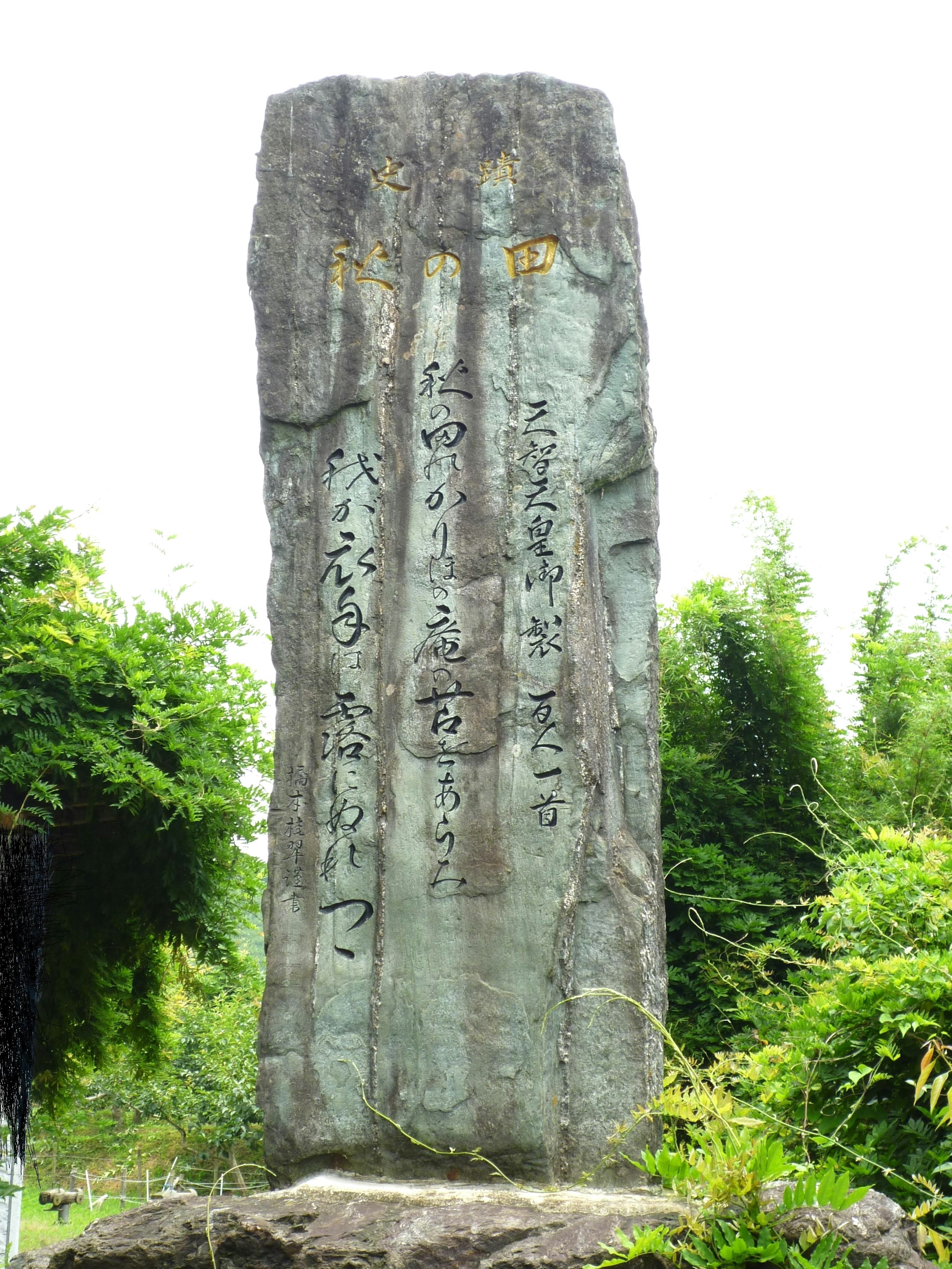 Un monumento de piedra con caracteres grabados rodeado de vegetación