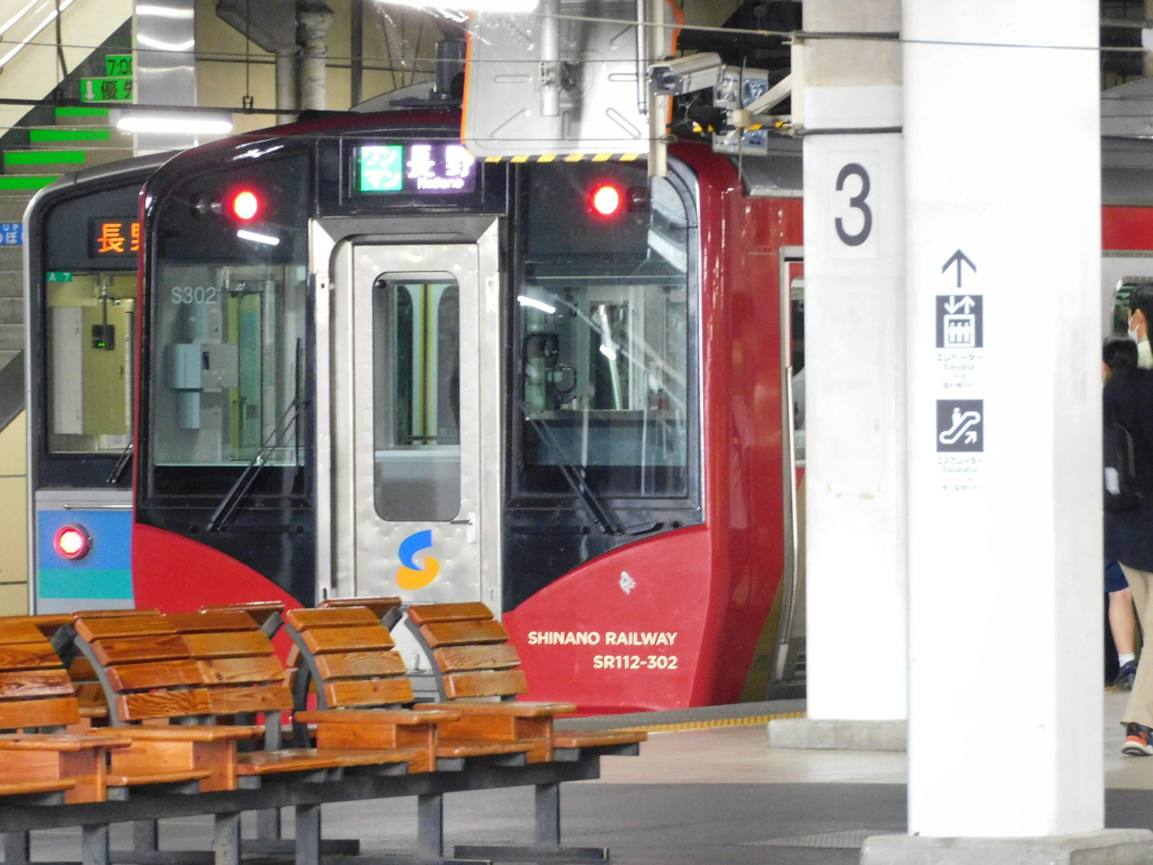 赤い電車が駅に停車している風景ベンチや柱が見える