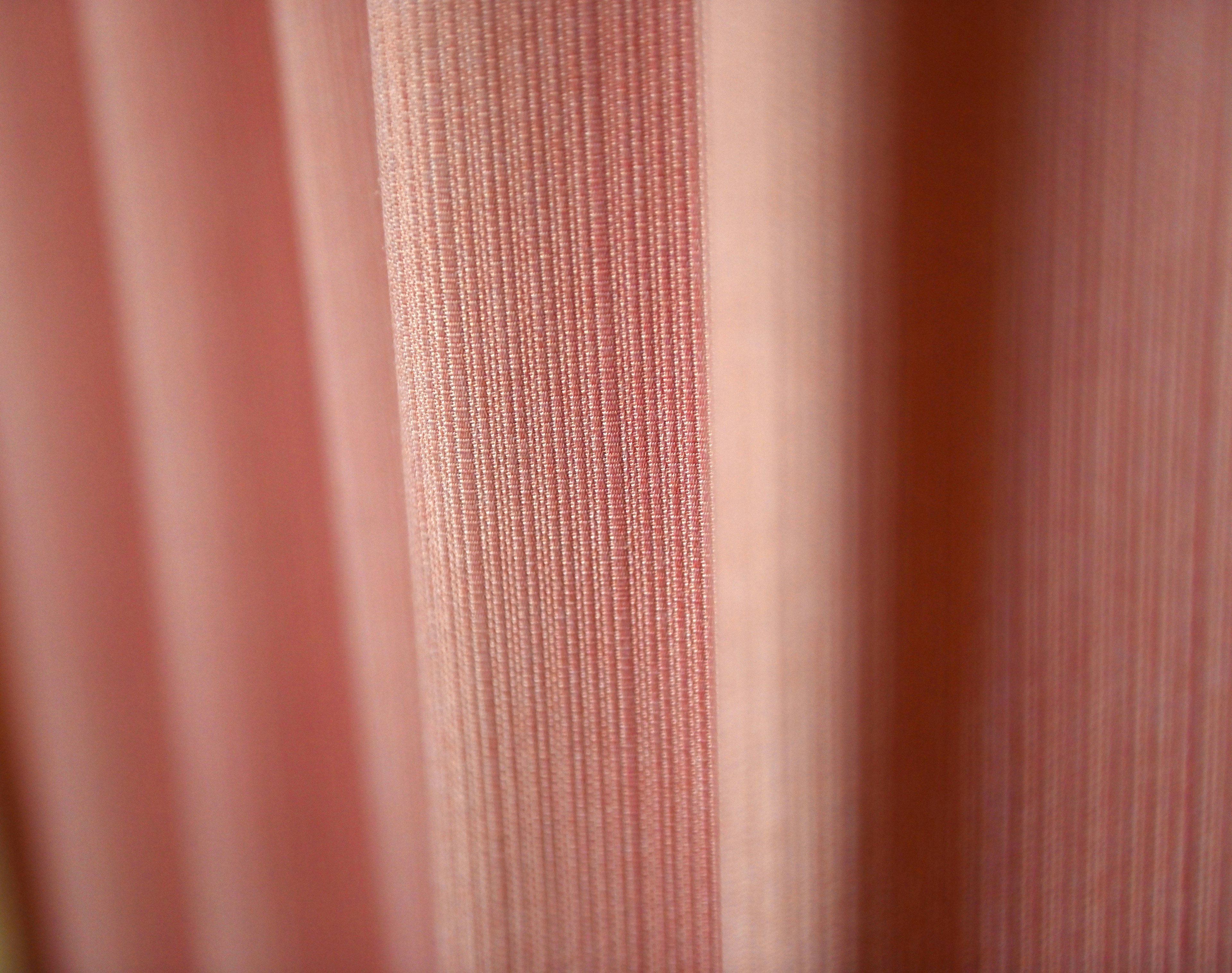 Close-up image of pink curtains featuring delicate striped patterns and soft texture