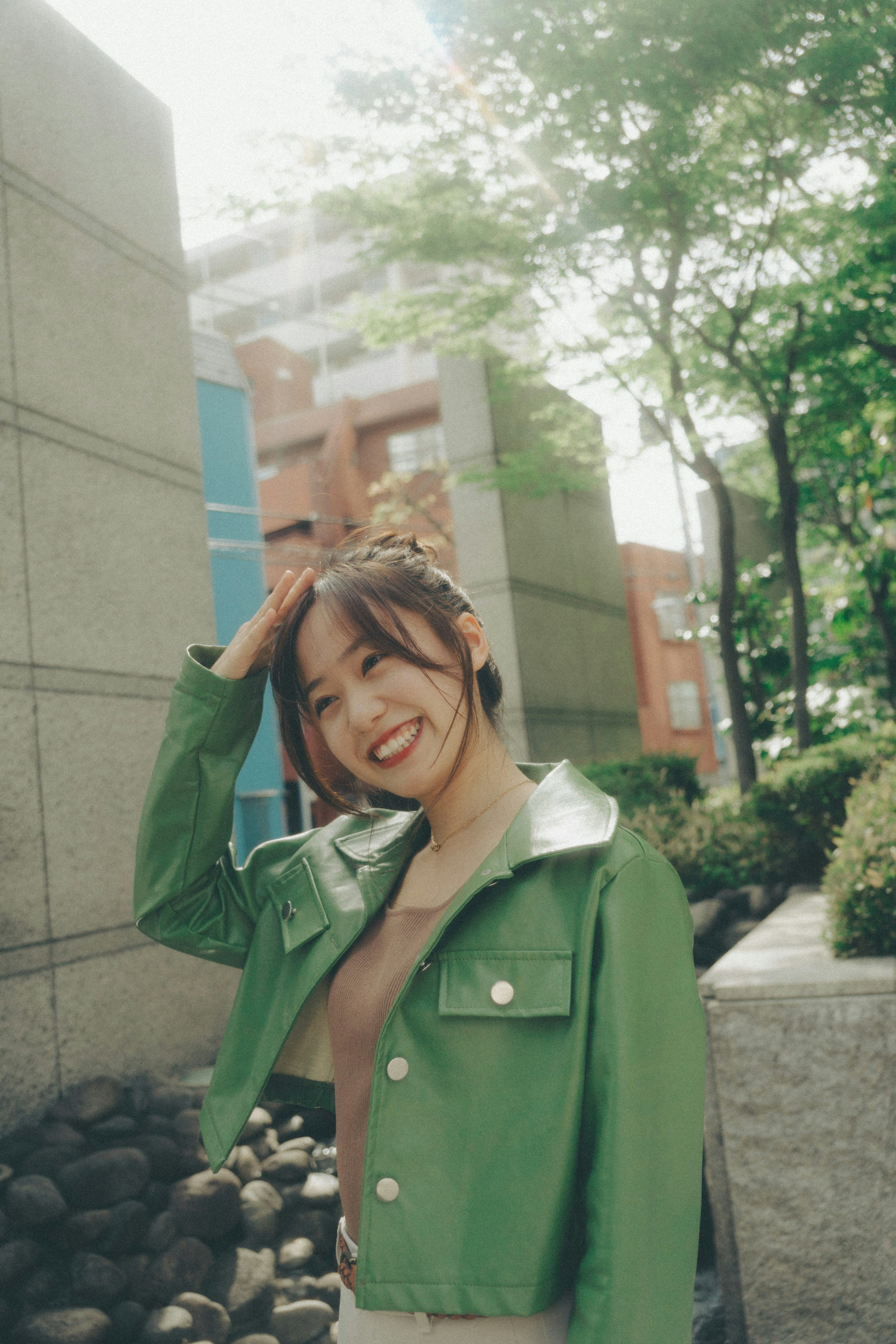 Woman in a green jacket smiling in a park setting