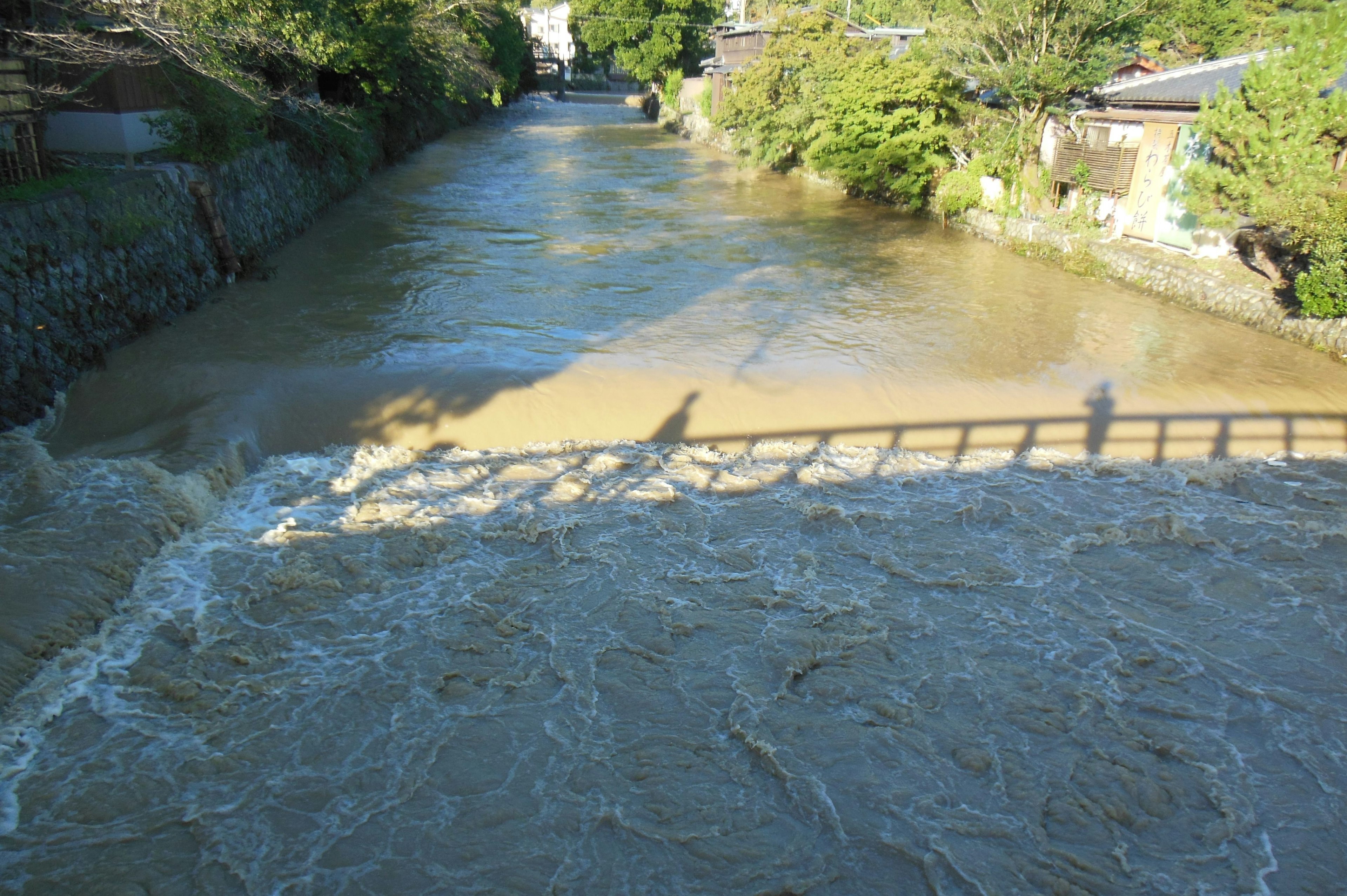 Une rivière boueuse avec des ombres de pont visibles